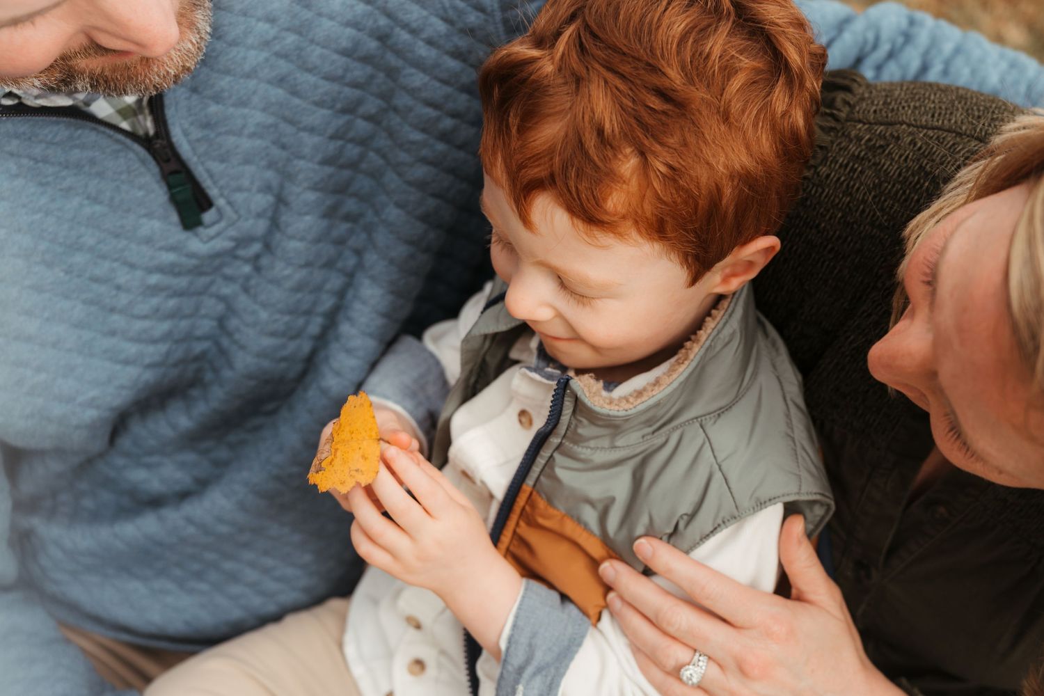 Little boy observing a golden leaf during this lifestyle family session at Five Blossoms Farm located in Clover, SC.