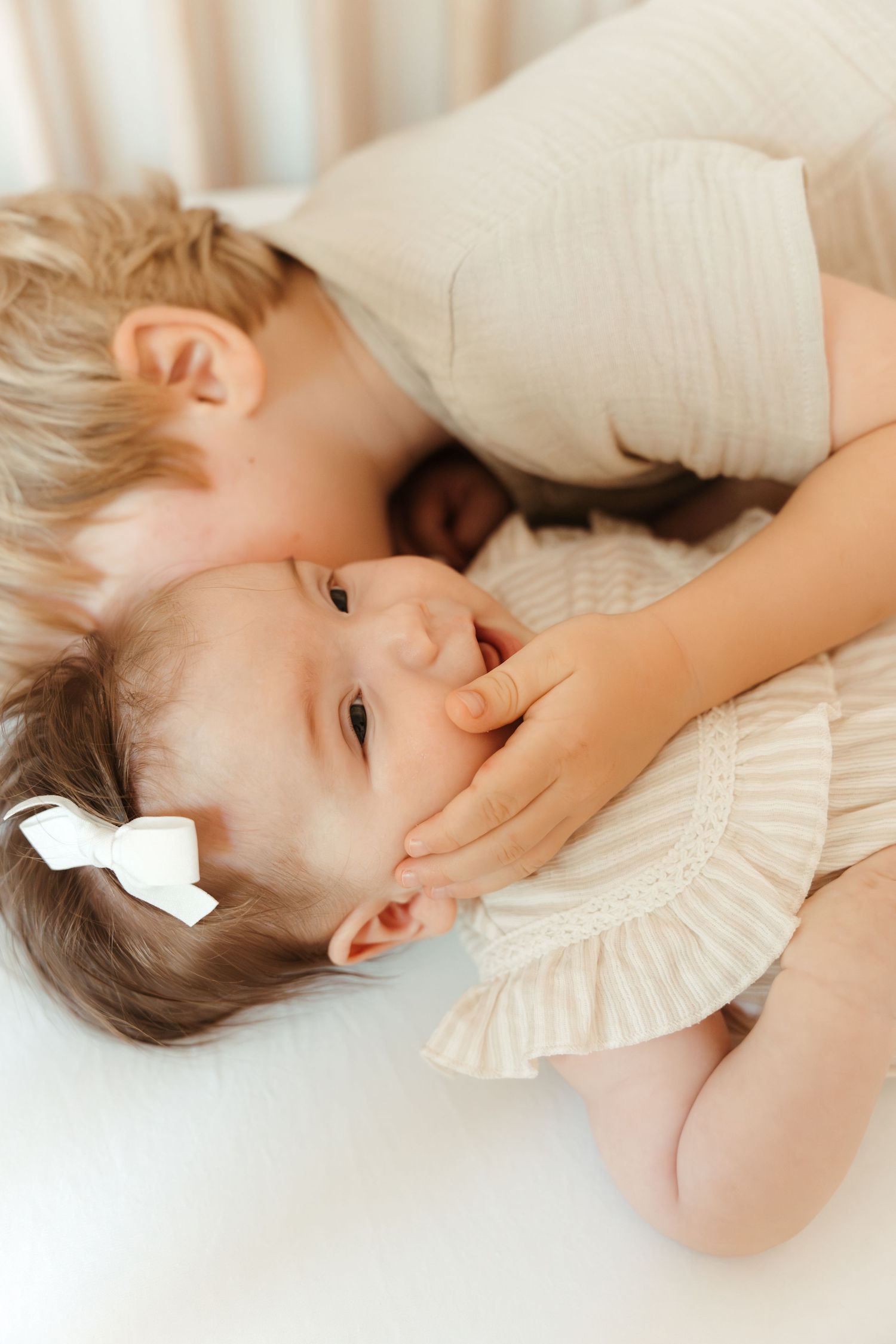 Siblings snuggled in a crib during an in-home family lifestyle session in Fort Mill, SC.