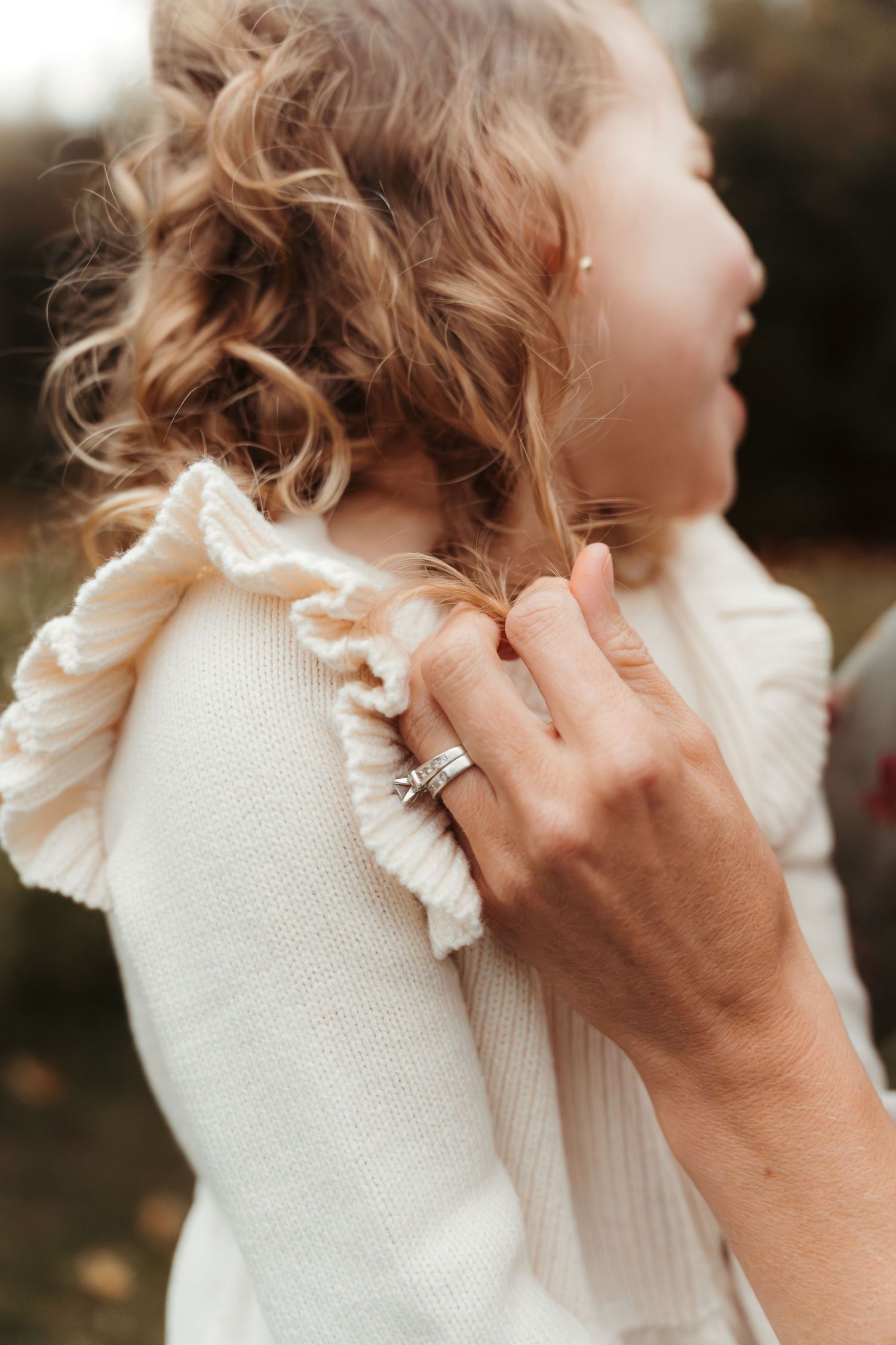 Mom twirling her daughter's hair during this lifestyle family session outdoors in Charlotte, NC.