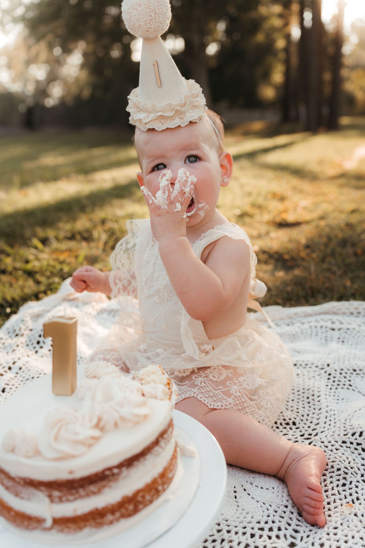 One-year-old sitting with birthday cake, smiling during an outdoor milestone cake smash session in Charlotte, NC.