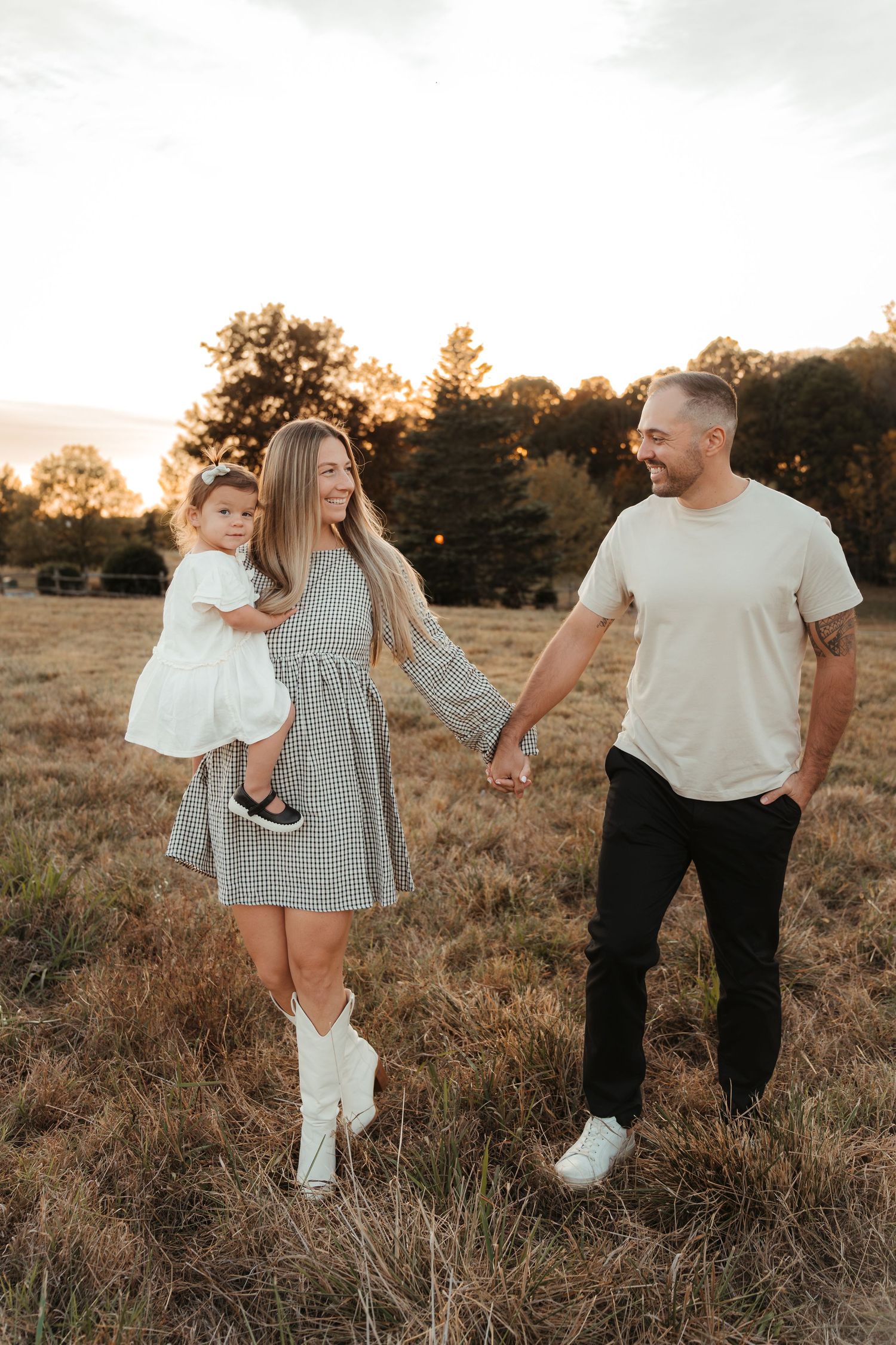 Family of three walking through a field during a golden hour family photo session in Fort Mill, SC.