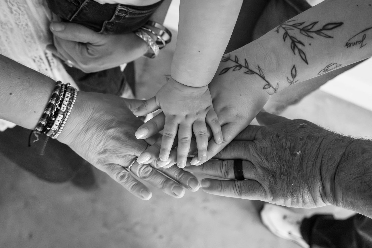 Black and white photo of multiple generations of hands stacked together, showing unity and family bonds.