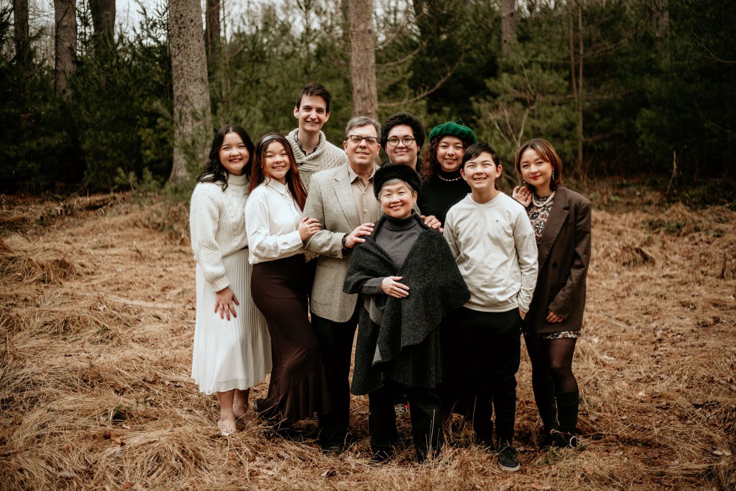 Extended family portrait in natural outdoor setting with pine trees.
