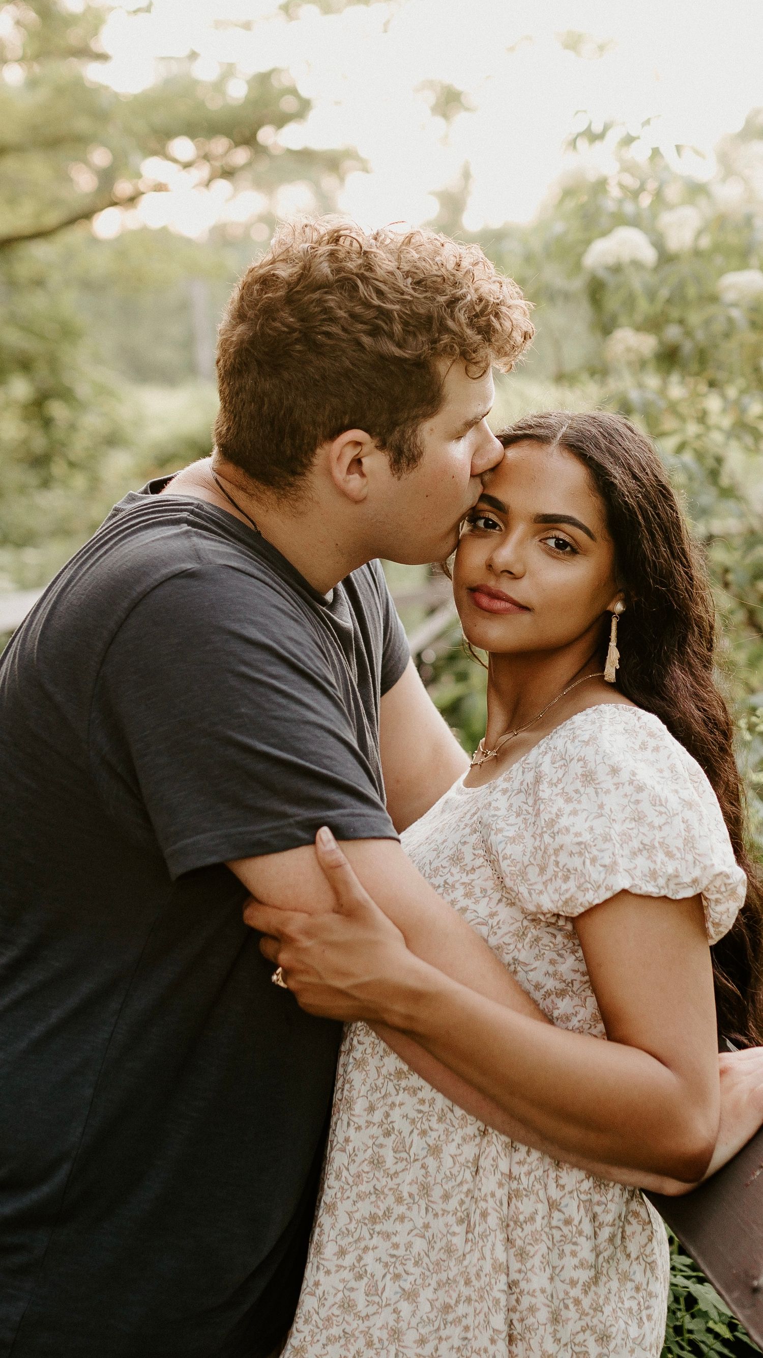 Romantic couple embracing outdoors during golden hour photoshoot.