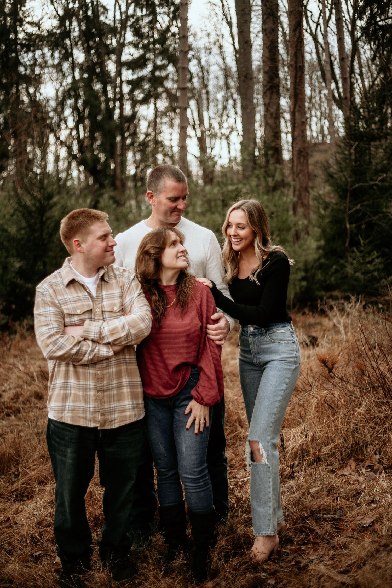 Romantic couple shares playful moments in a wooded outdoor setting during engagement photoshoot.
