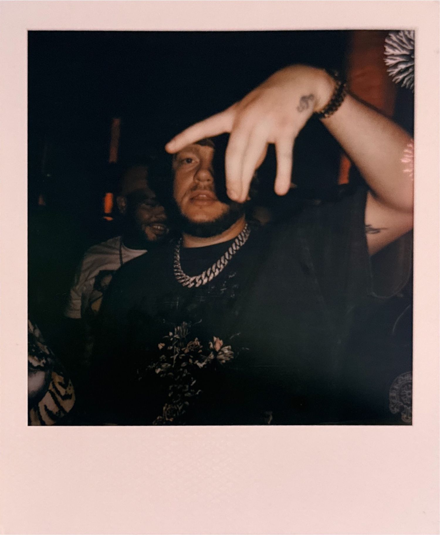 Dark nightclub scene with hands raised and jewelry visible.