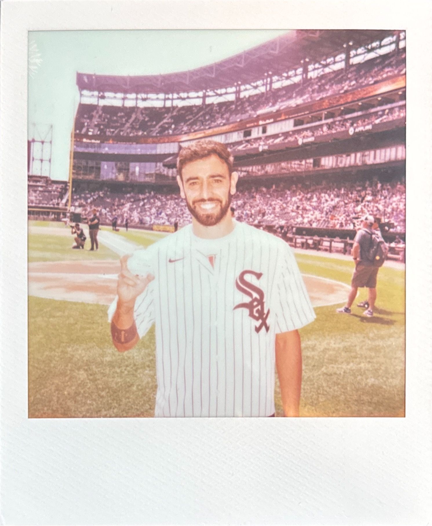 Baseball player in Chicago White Sox pinstripe uniform smiling on field.