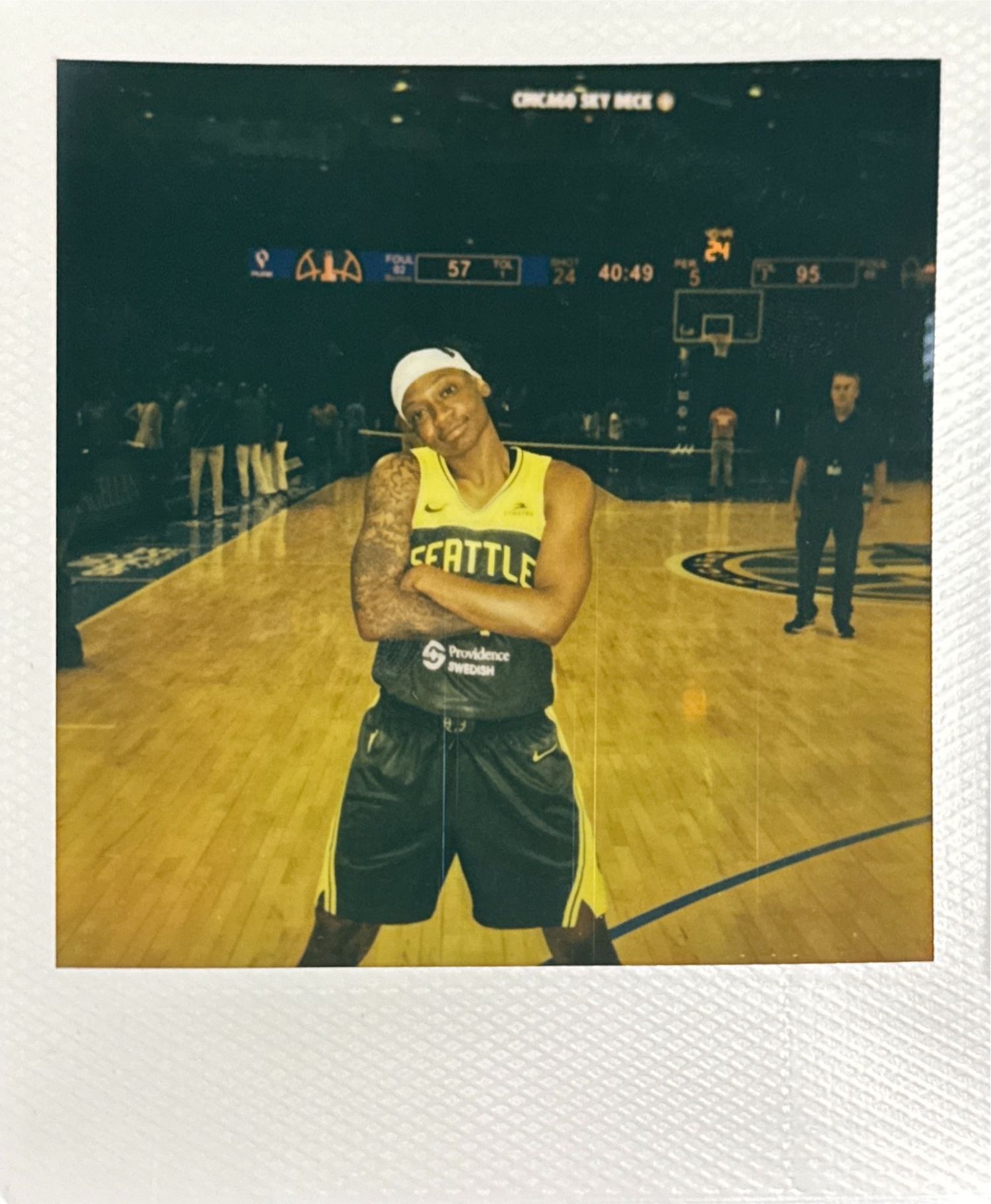 Basketball player stretching on wooden court in Seattle Storm jersey.