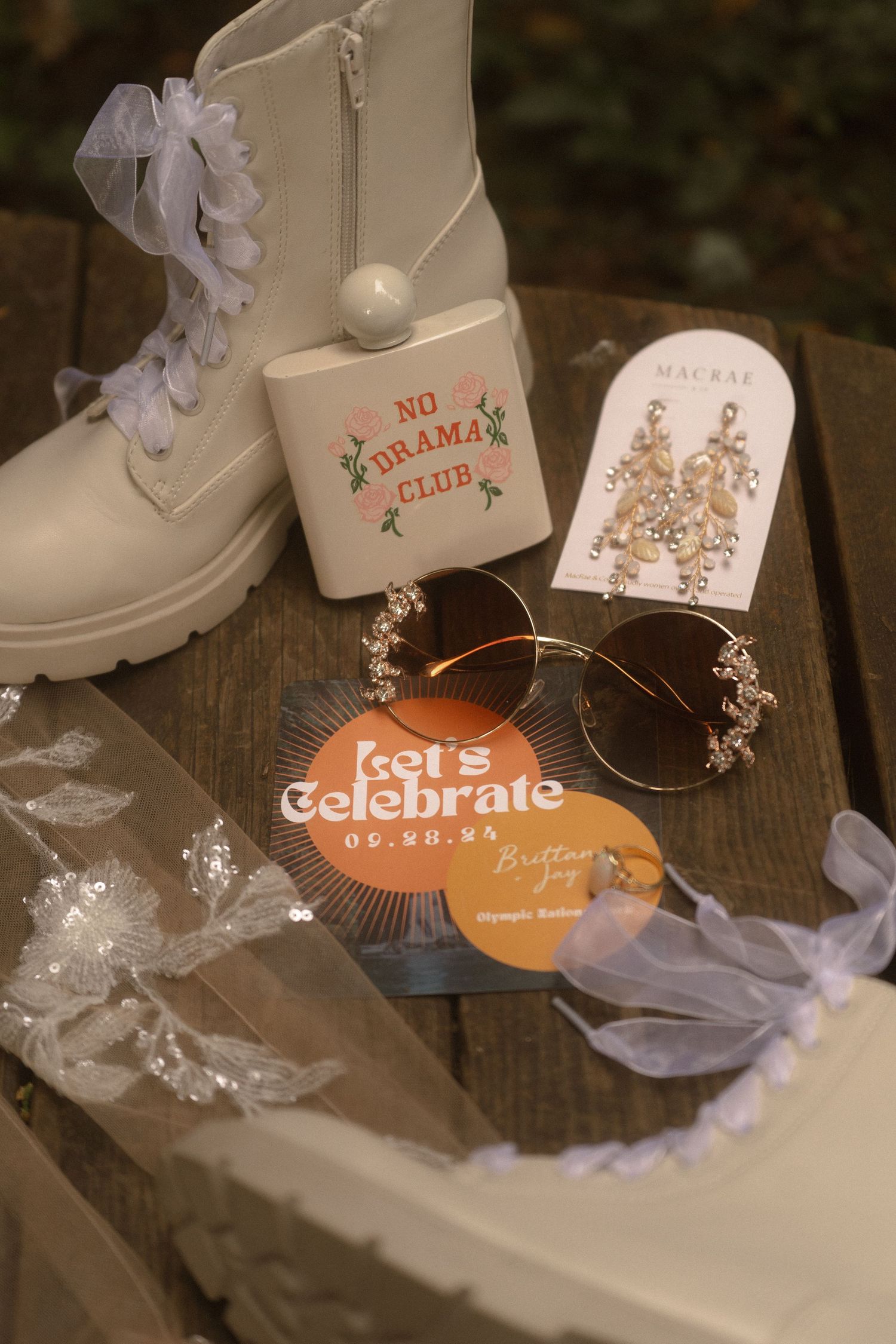 retro vintage flat lay of all details including flask, earrings, invitations, sunglasses, and boots