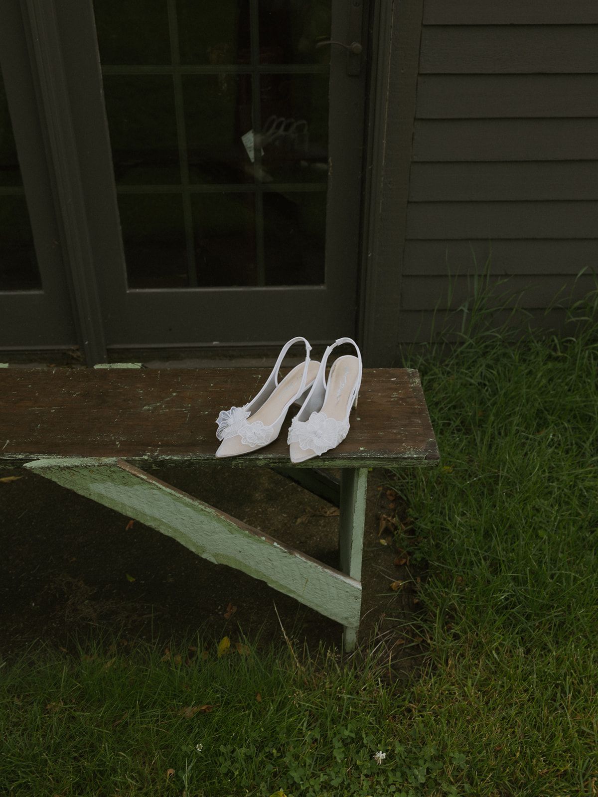 detail photo of wedding heels on a bench, green tones, moody