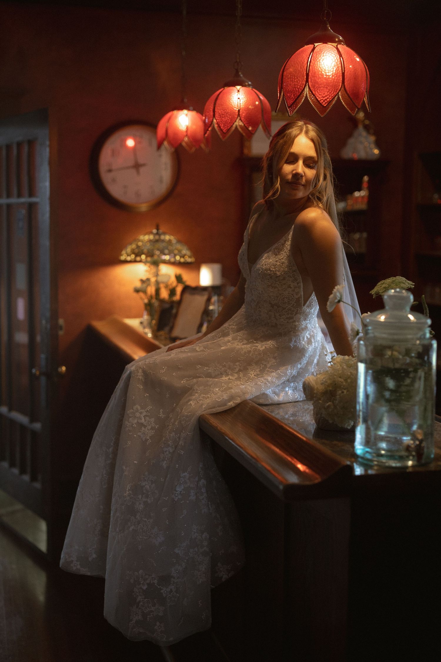 a bride sitting by the bar, low lighting, vintage floral lamps, moody bride