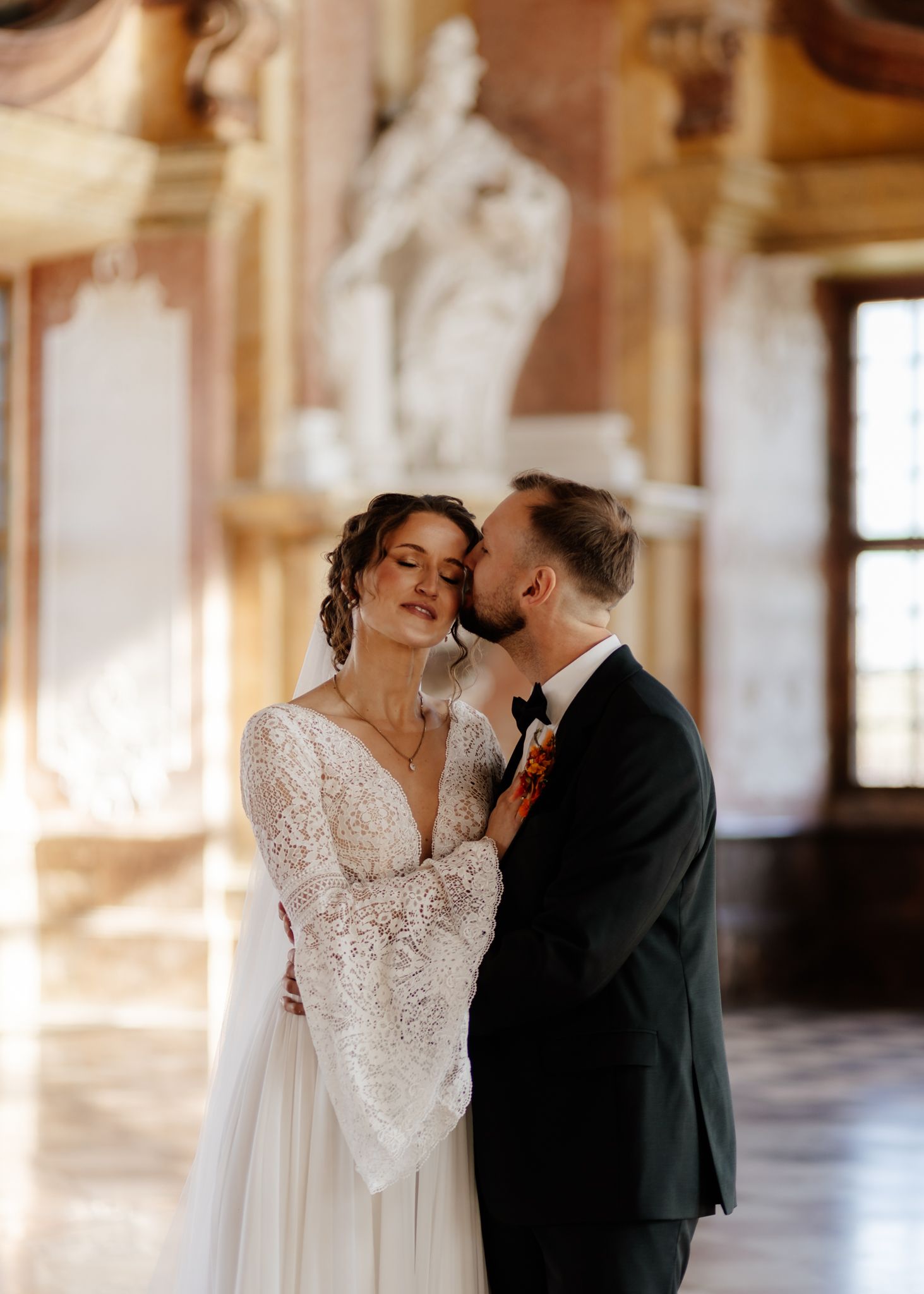 Romantic wedding photoshoot in an ornate historic building with natural light streaming in.