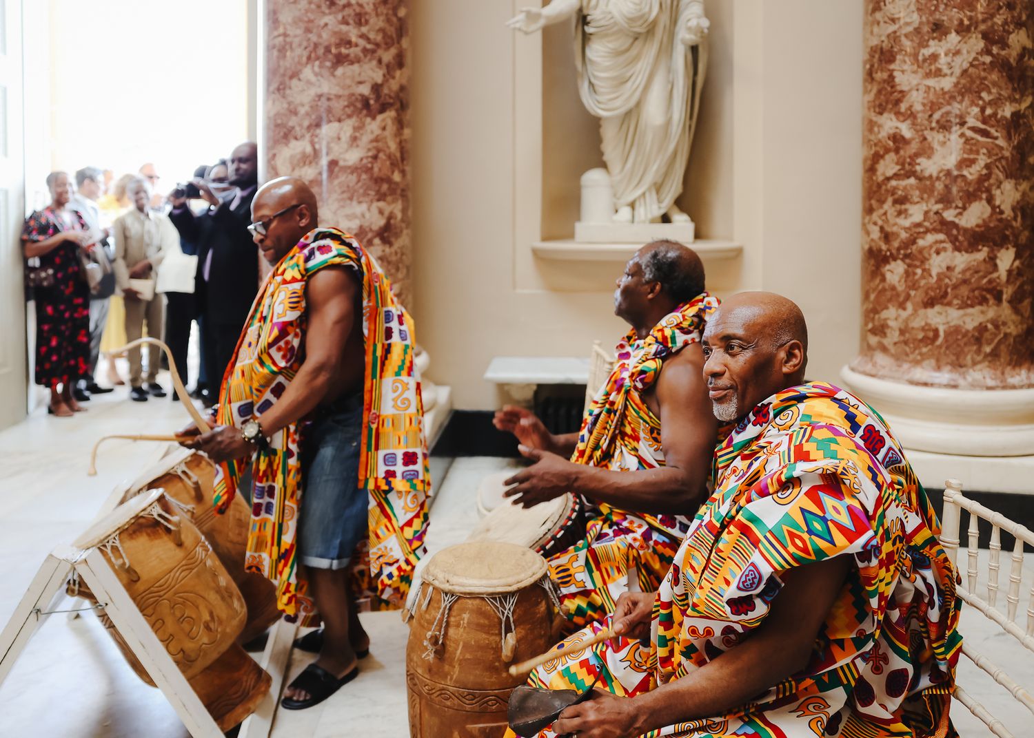 Musicians in colorful traditional attire playing drums during wedding celebration.