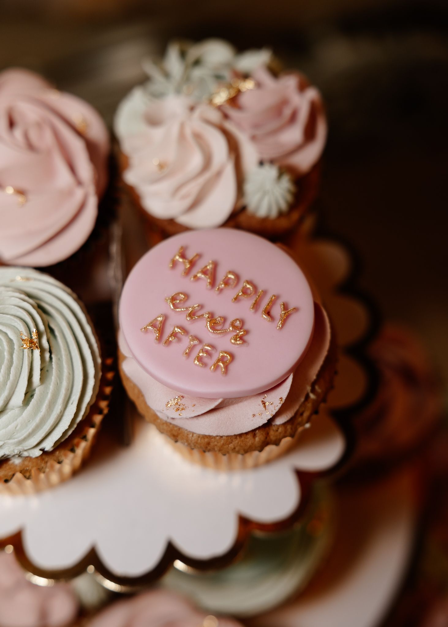 Pink heart-shaped candy decorations and pastel frosted cupcakes arranged in a romantic Valentine's Day display.