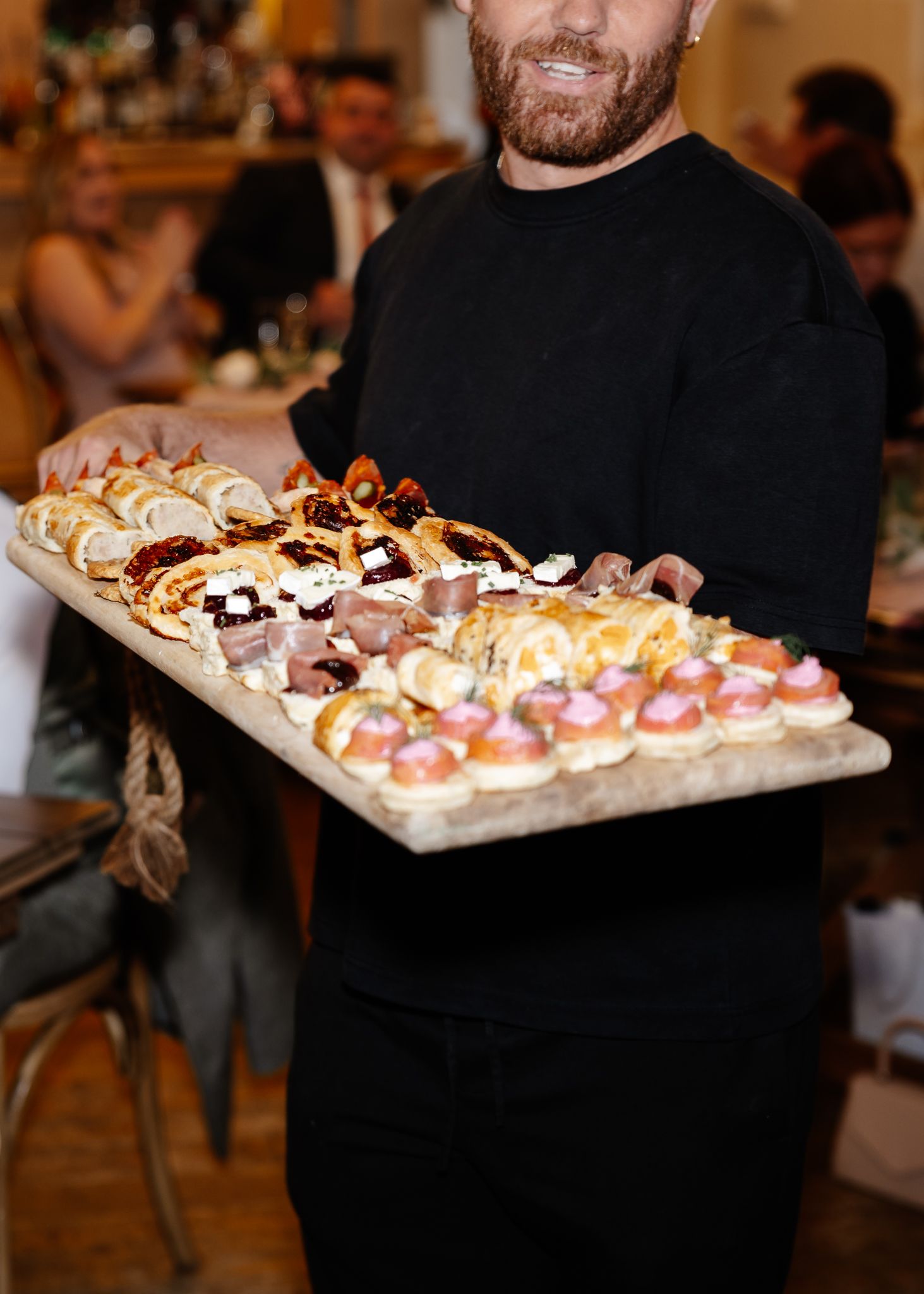 A series of appetizer platters being presented at an indoor event with warm lighting and elegant displays.