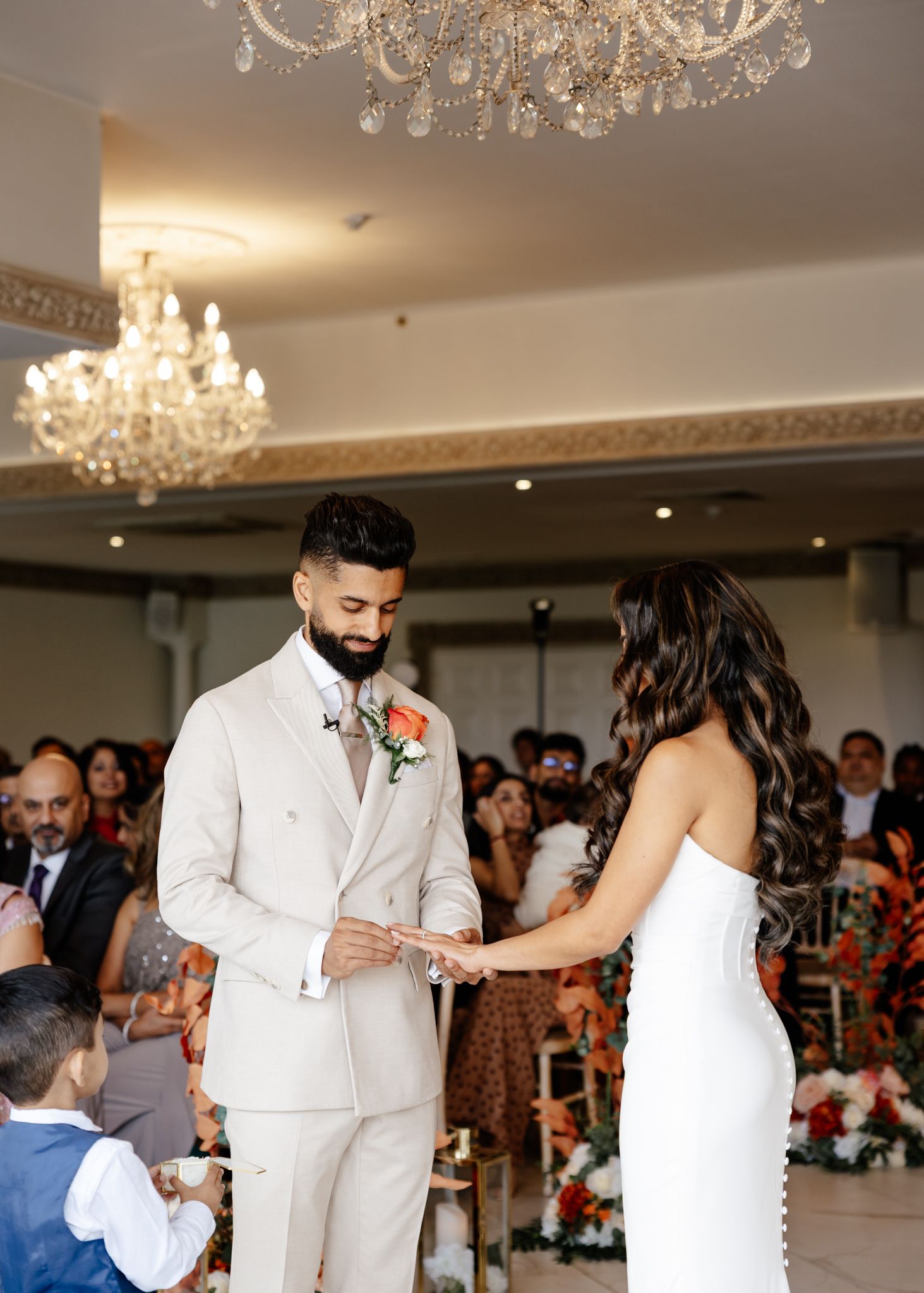 Wedding celebration in an elegant ballroom with crystal chandeliers and guests watching the couple.