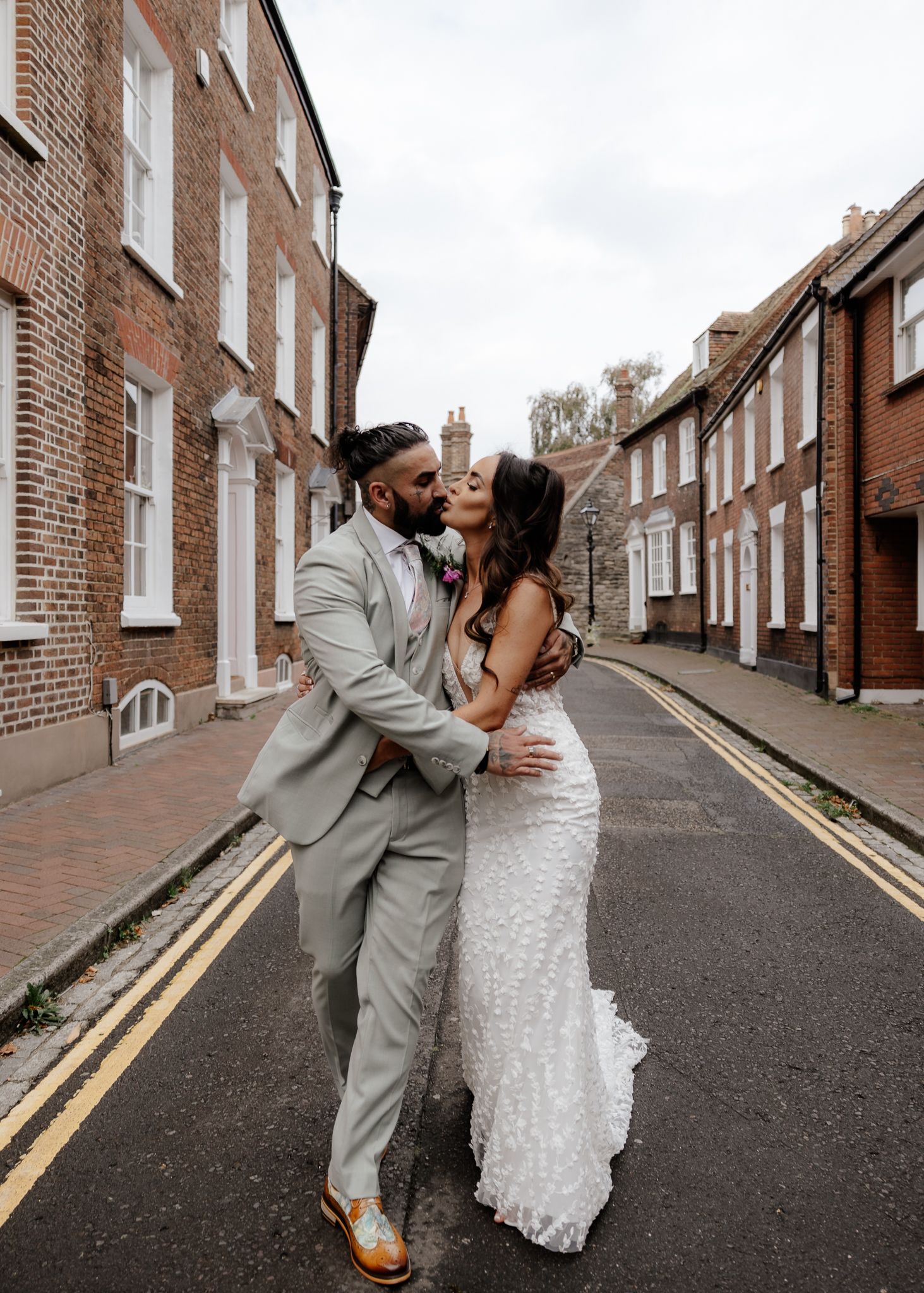 A couple in wedding attire shares romantic moments on a brick-lined street, captured in a series of candid photos.
