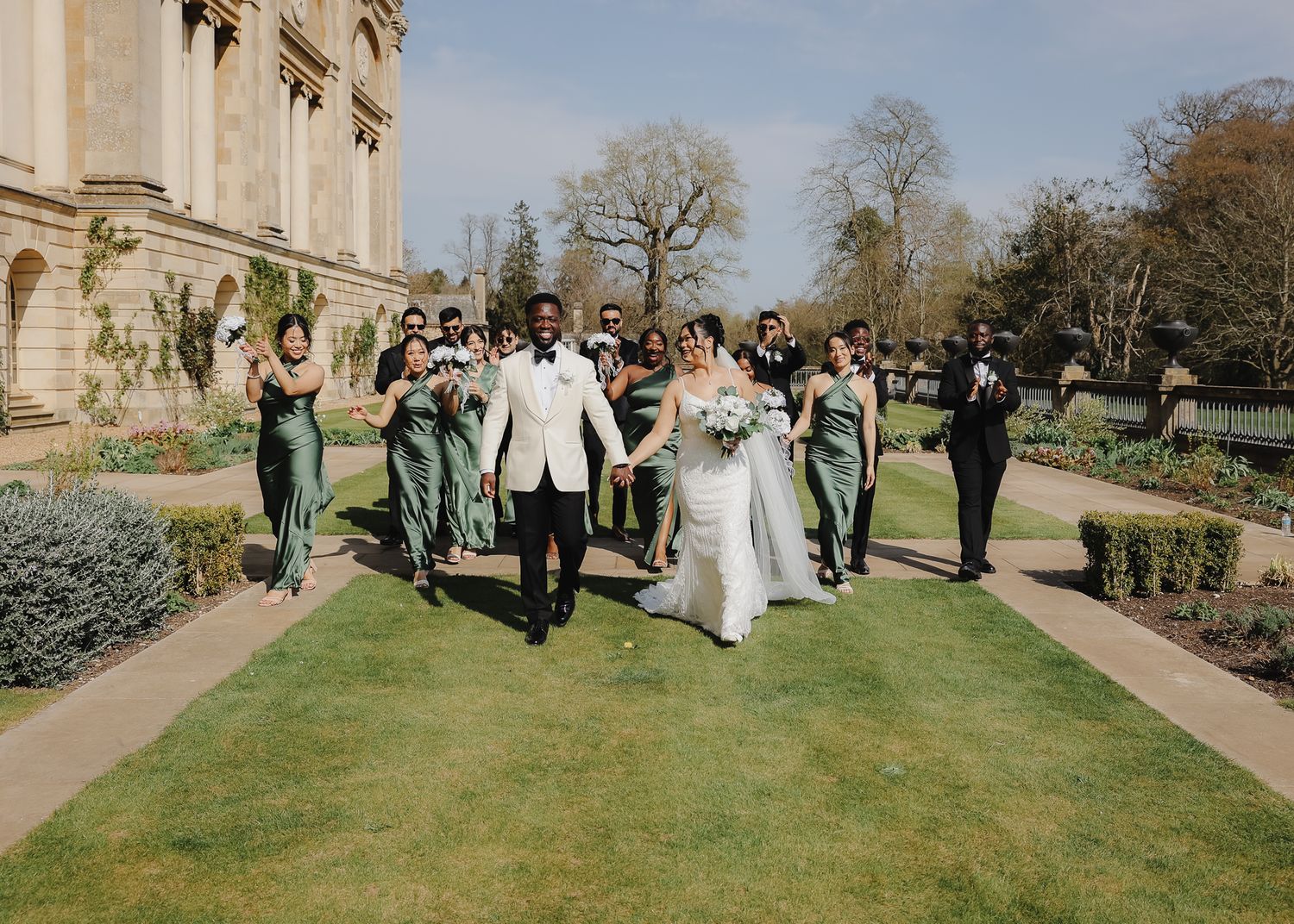A wedding celebration on a sunny day outside a grand stone church with guests gathered on the lawn.