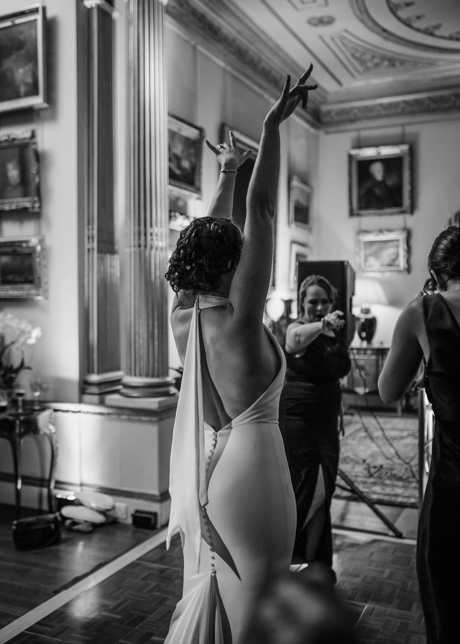 Ballet dancers practice at a barre in an ornate studio with mirrored walls and decorative moldings.