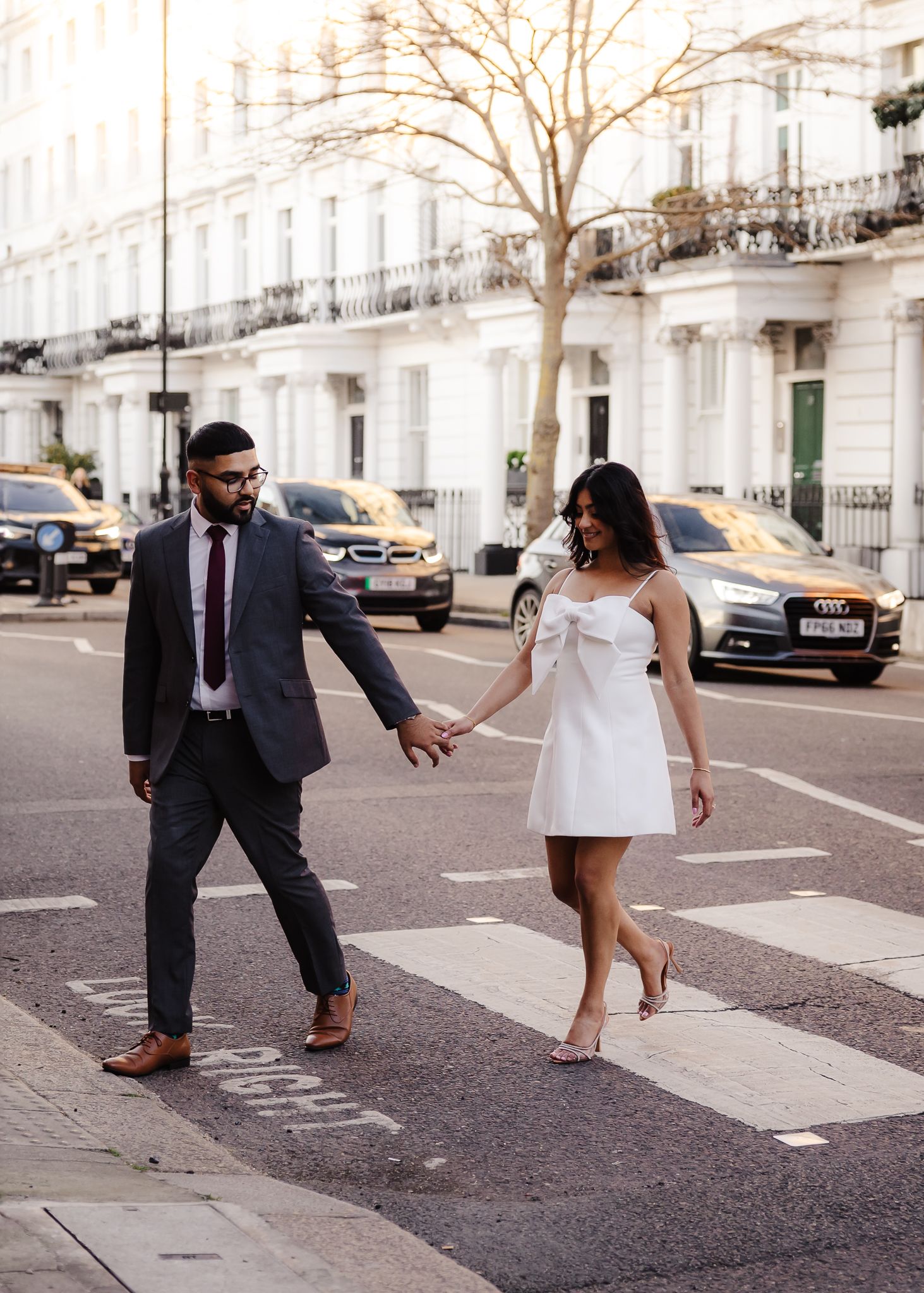 Stylish couple crossing street in London, woman in white mini dress, man in grey suit.
