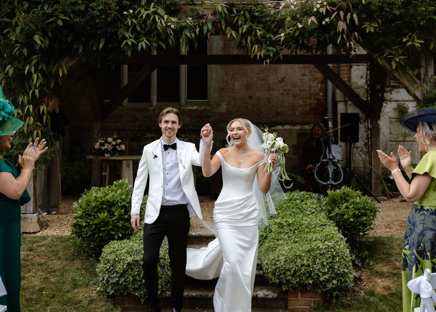 Bride and groom celebrating as they walk back down the aisle after their outdoor garden wedding ceremony.
