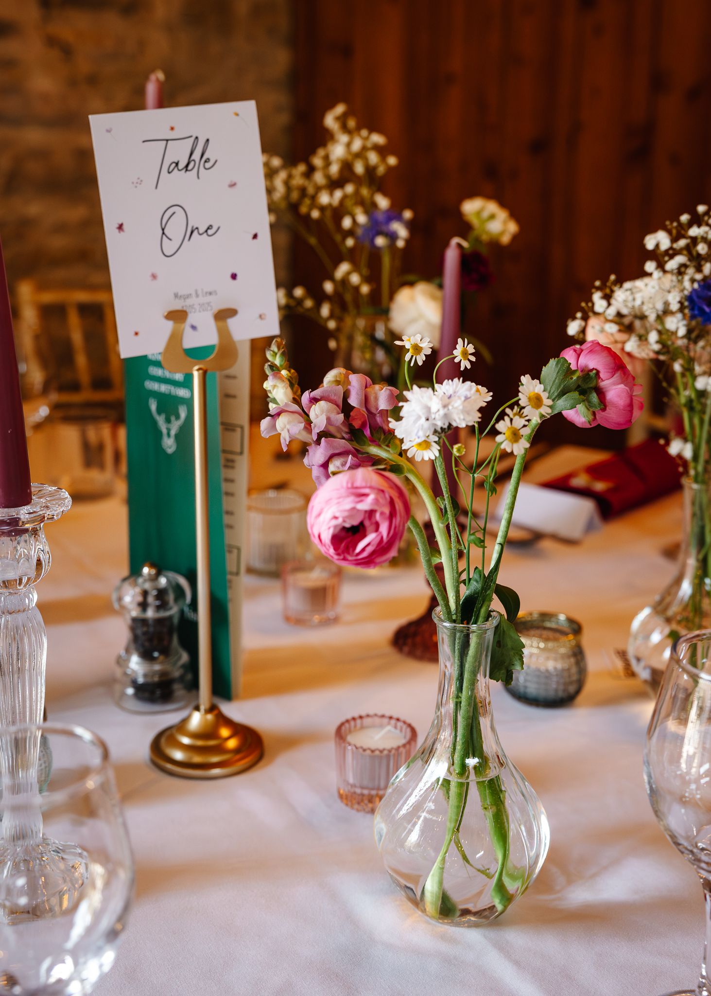 Elegant wedding reception table setting with white linens, delicate floral centerpieces, and table number cards.