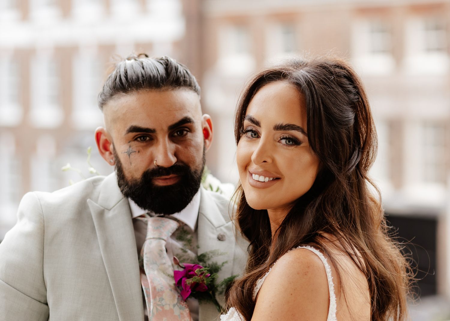 A happy couple shares an intimate moment during their wedding celebration with blurred background.