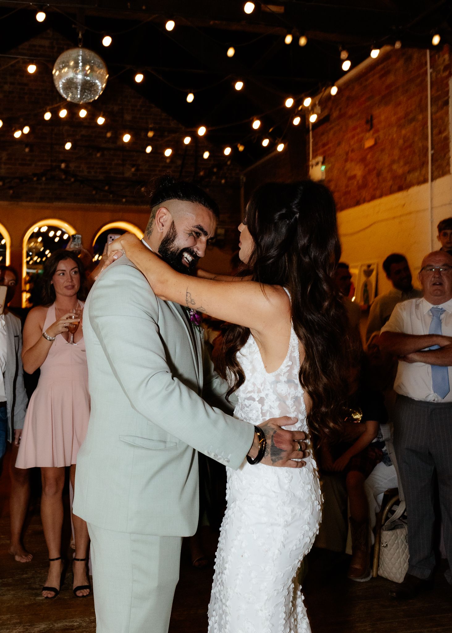 Couple shares their first dance under twinkling lights at a romantic wedding reception venue.
