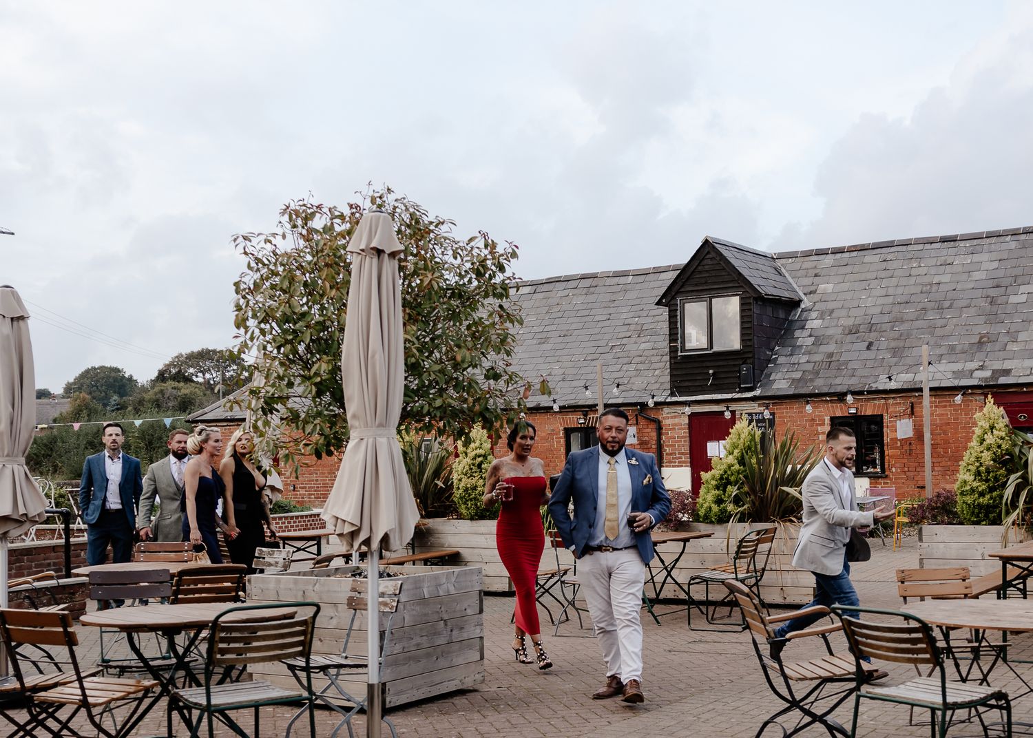 Panoramic view of a rustic outdoor terrace with wooden benches and umbrellas overlooking a scenic landscape.