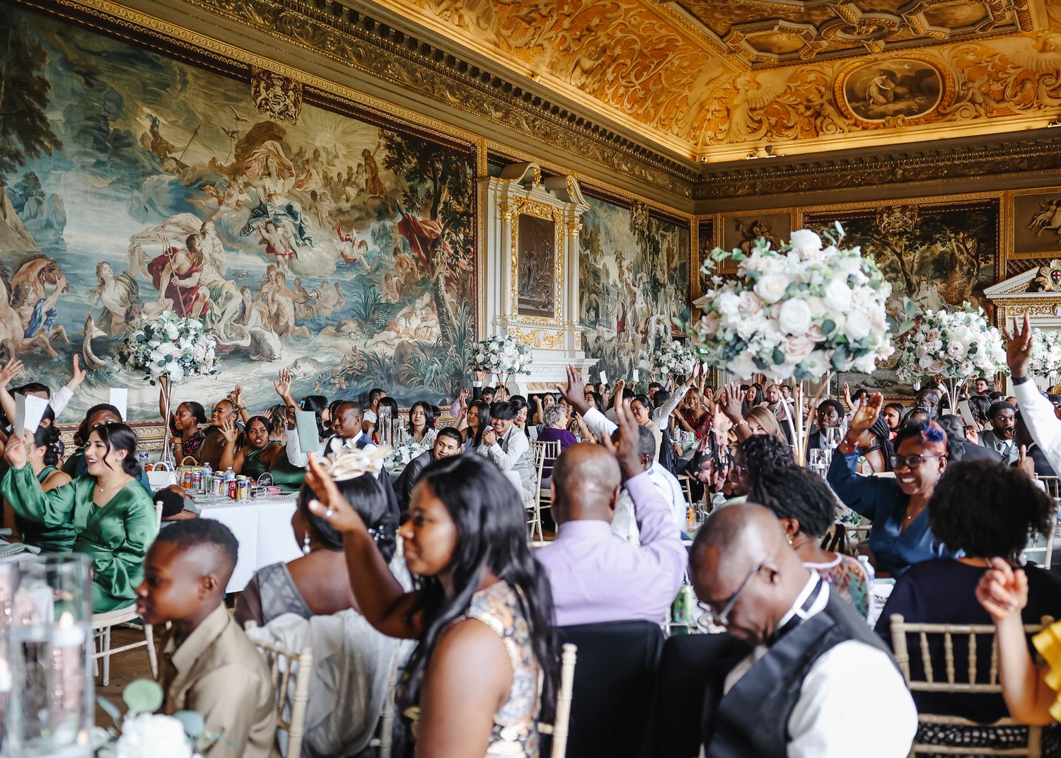 Wedding reception panorama in grand historic hall with painted ceilings and elegant table settings.