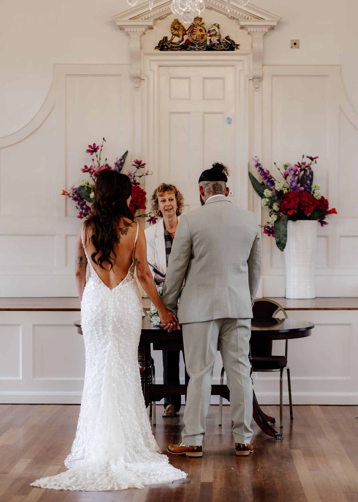 A series of candid wedding ceremony moments showing a couple signing documents in an elegant white room with floral decor.