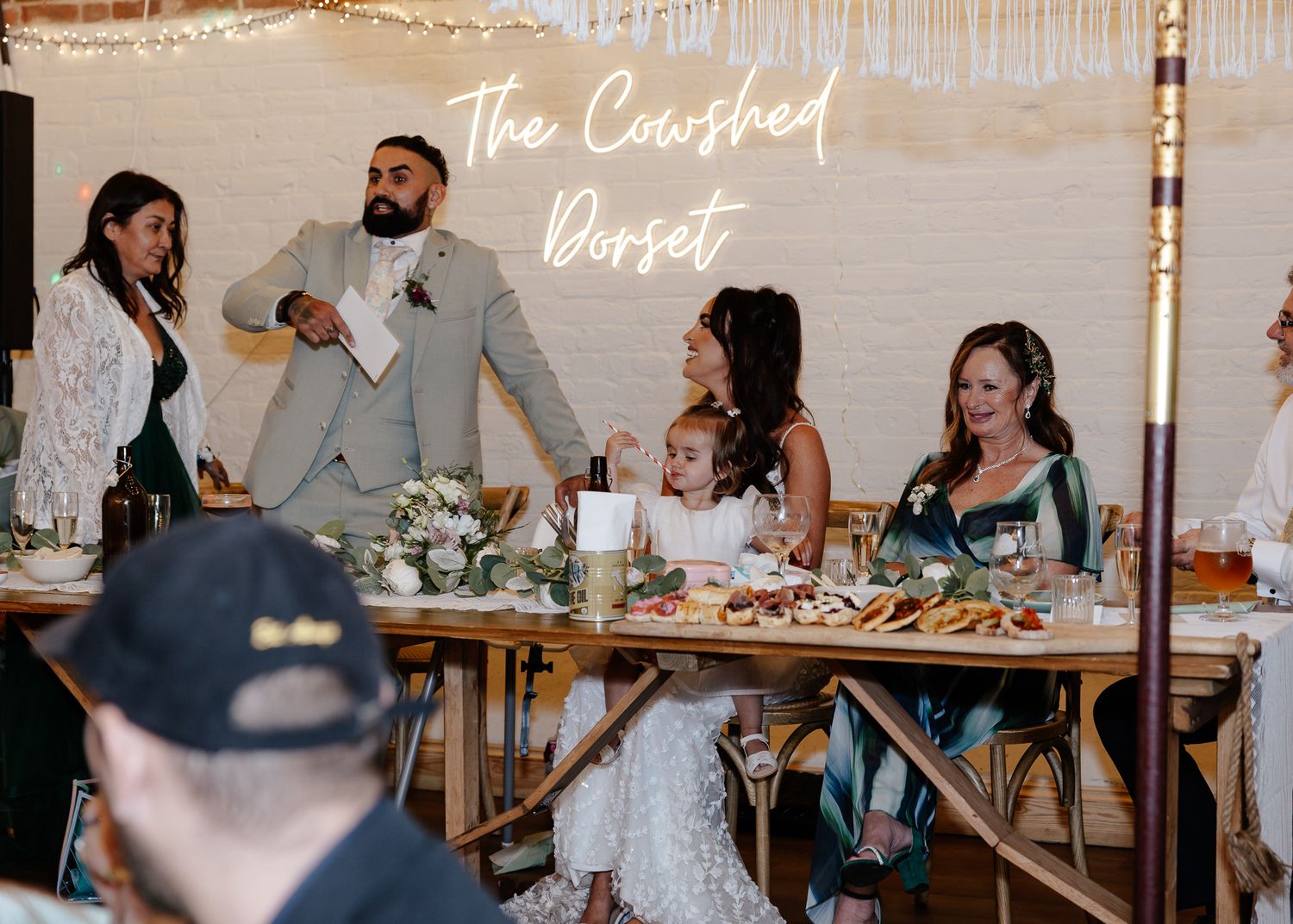 Wedding guests gather around rustic wooden tables at an intimate reception dinner celebration.