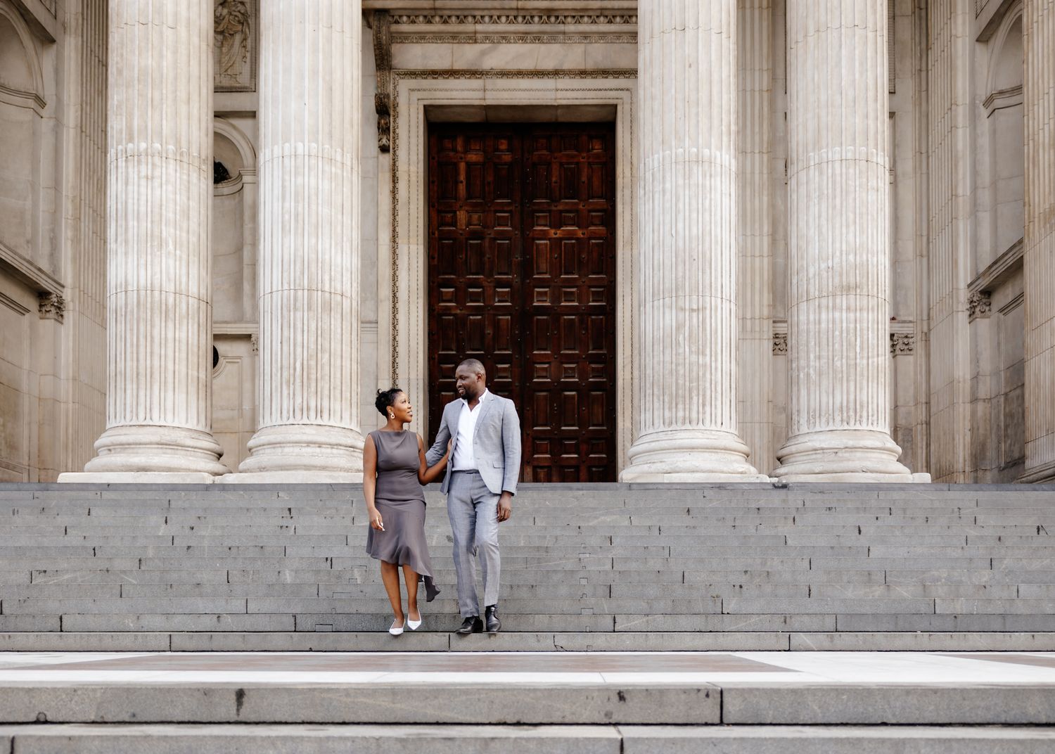 Architectural detail of grand stone columns and steps at a historic building entrance with visitors in the background.