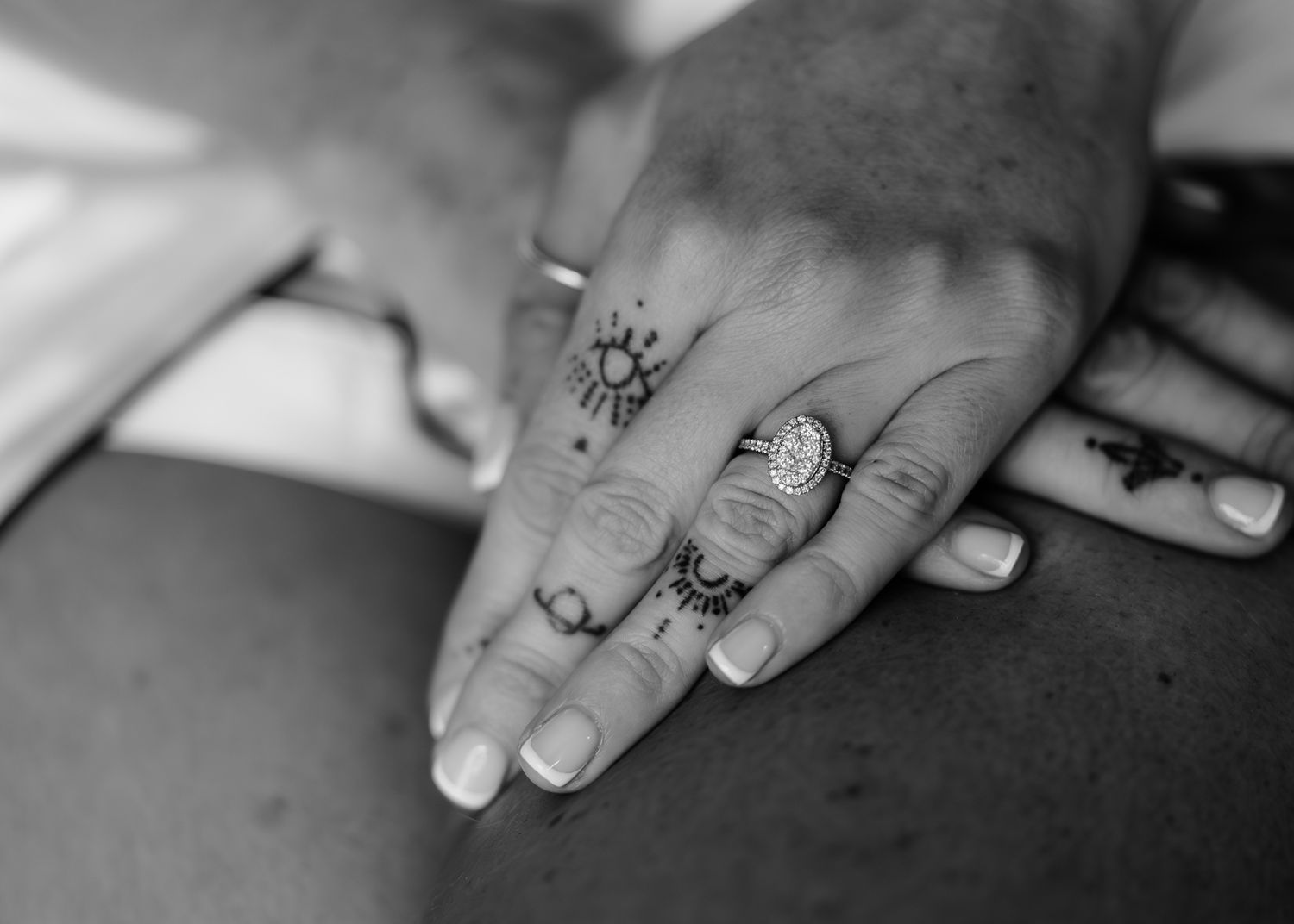 A close-up black and white photo shows hands delicately working with small objects on a flat surface.