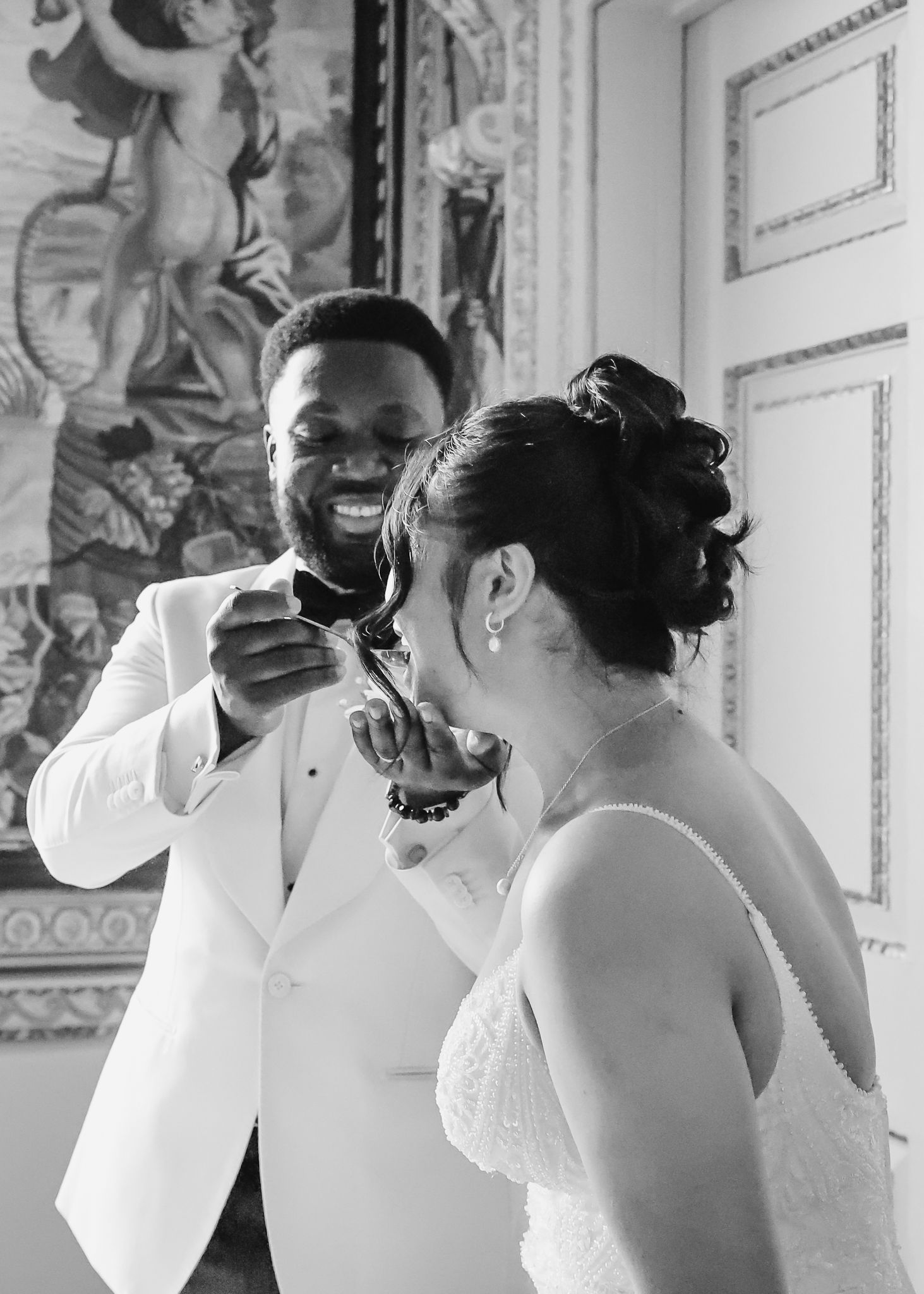 Wedding party laughing and celebrating in elegant white room with ornate details.