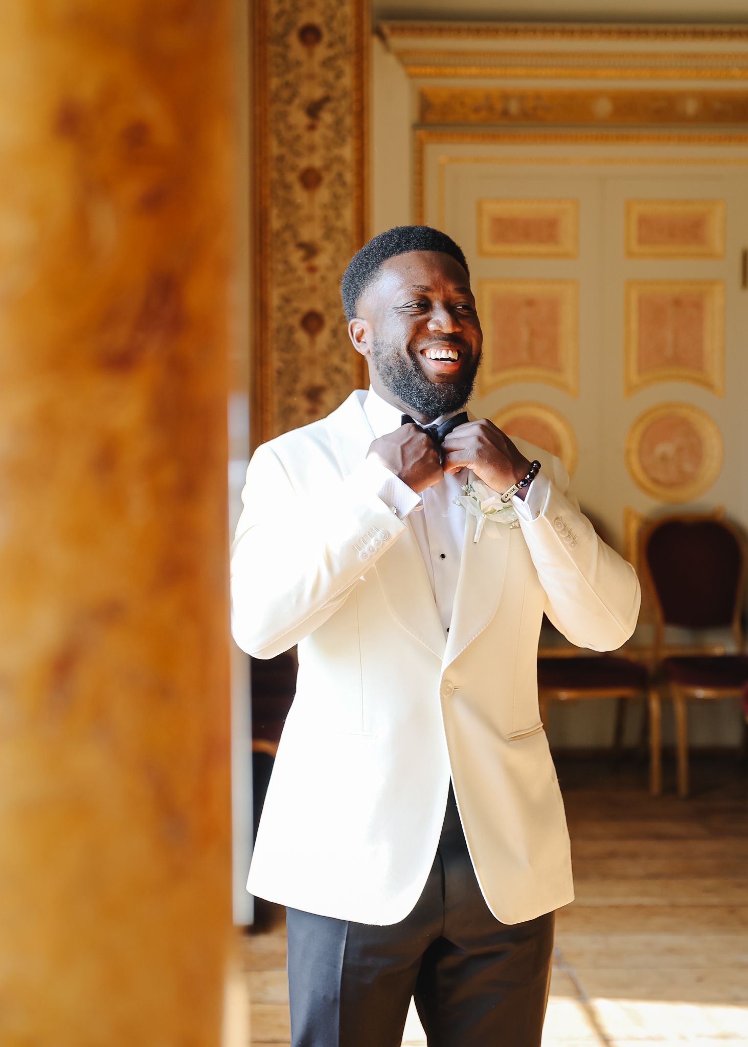 A performer in a white tuxedo jacket sings passionately on stage in an ornate venue with golden decor.