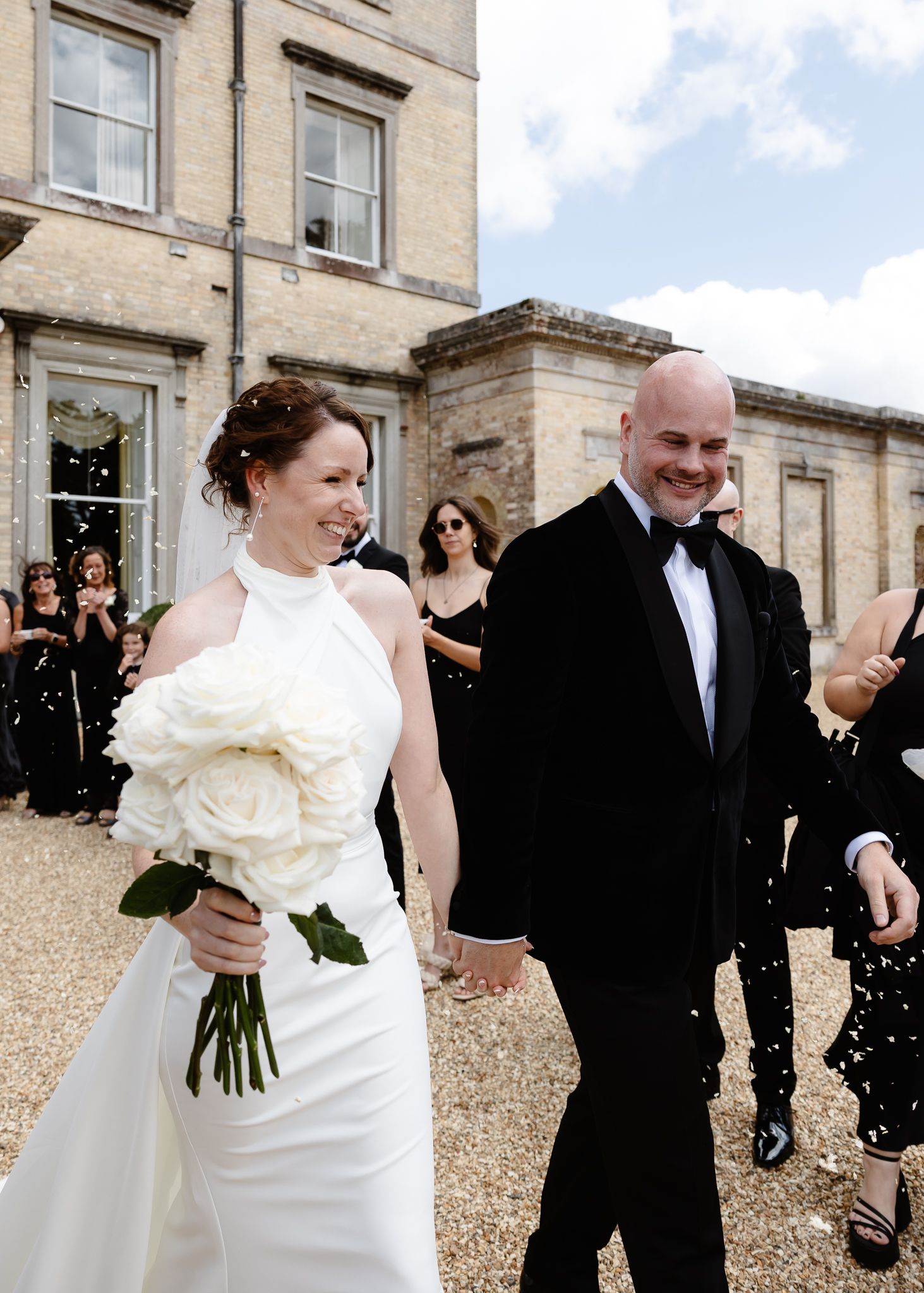 A joyful wedding couple exits their ceremony while holding hands, with the bride carrying a white bouquet.