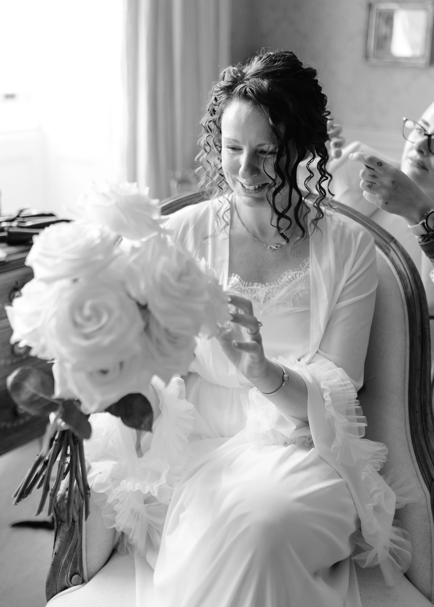 A series of black and white photos showing a bride in a white dress getting ready with her wedding party.