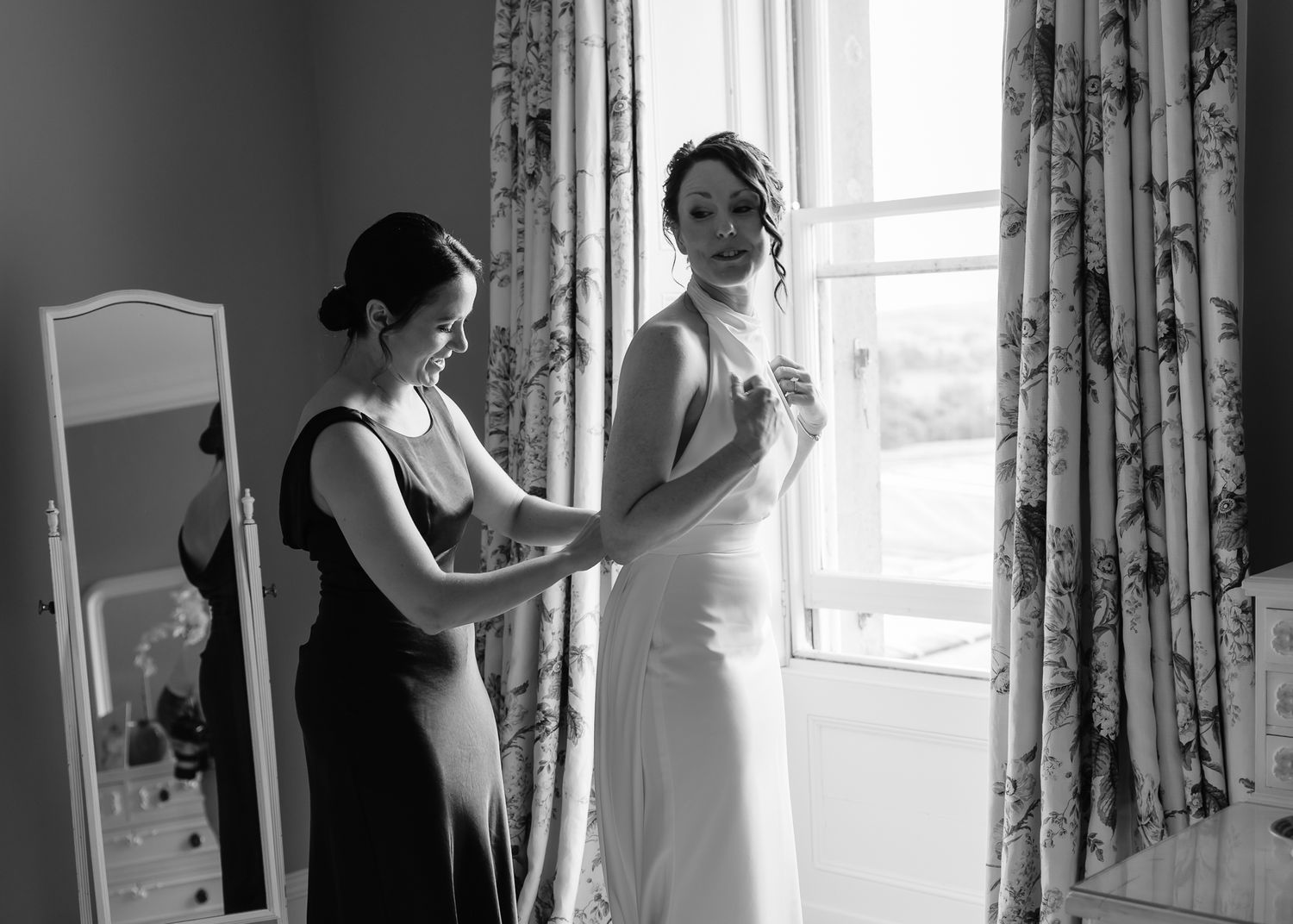 Black and white photos showing people preparing by window with flowing curtains in bright room.