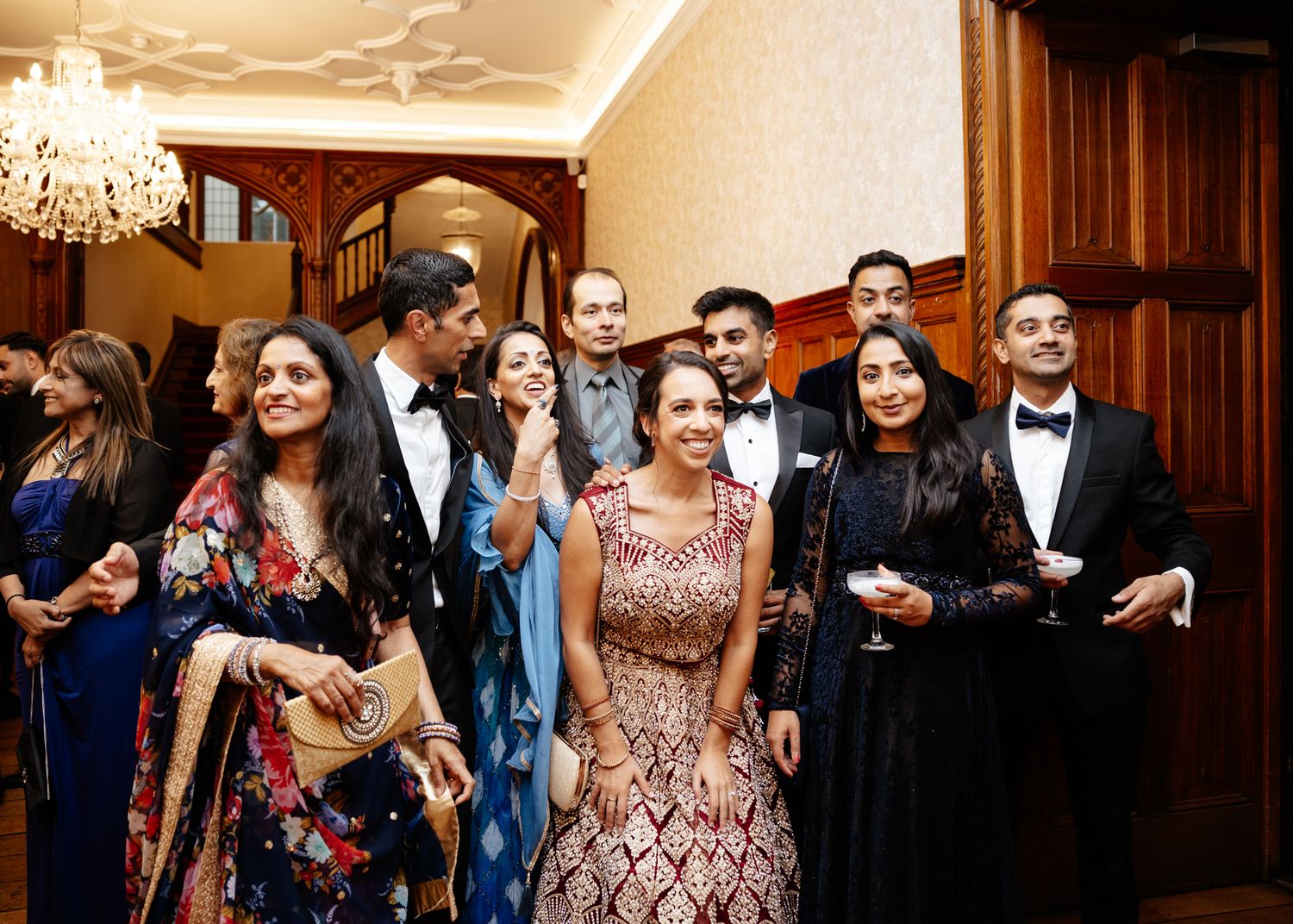 Wedding guests dance and celebrate together on the dance floor during an elegant reception with chandeliers.