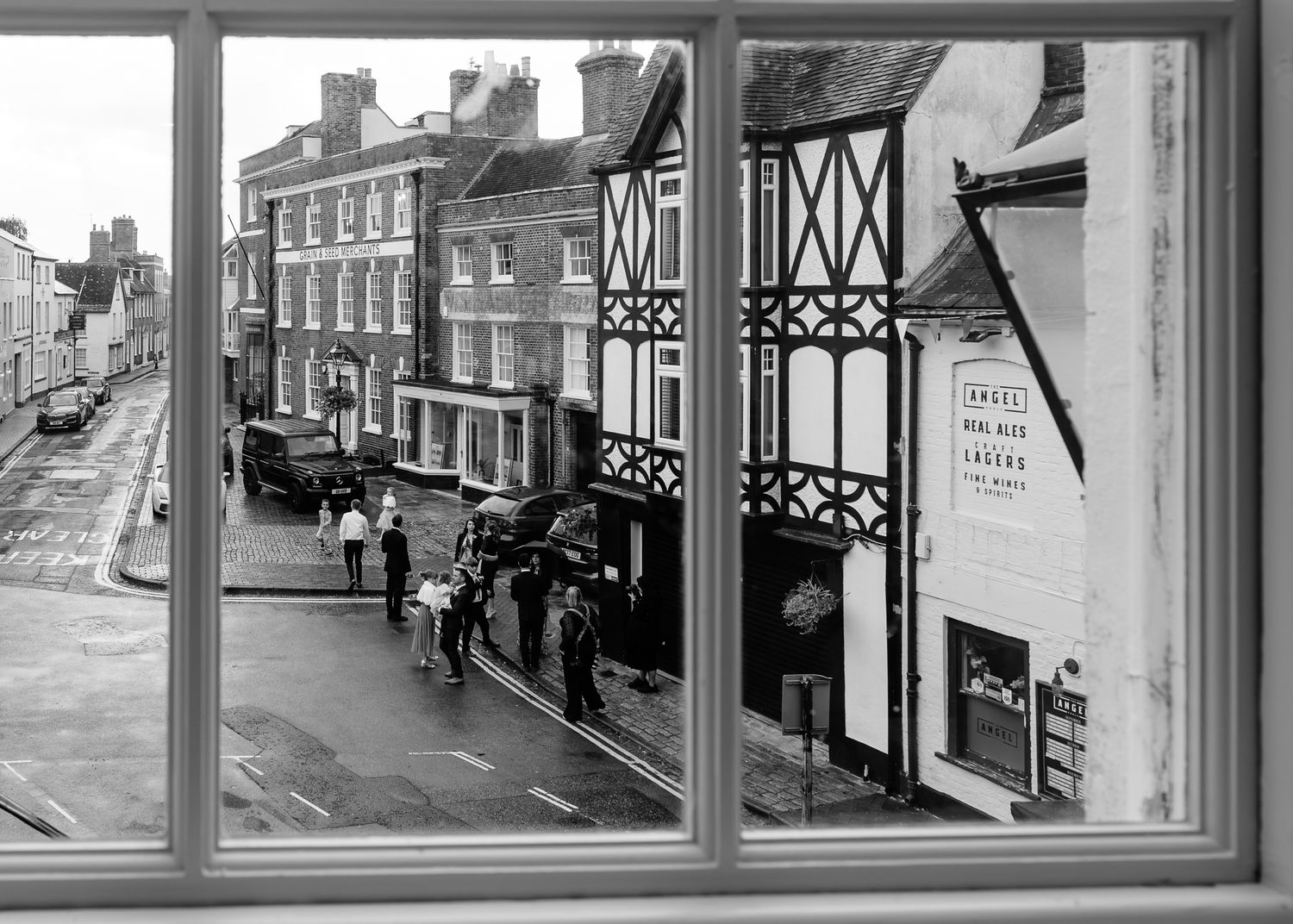 A row of windows frames views of a historic brick street with traditional English architecture and storefronts.