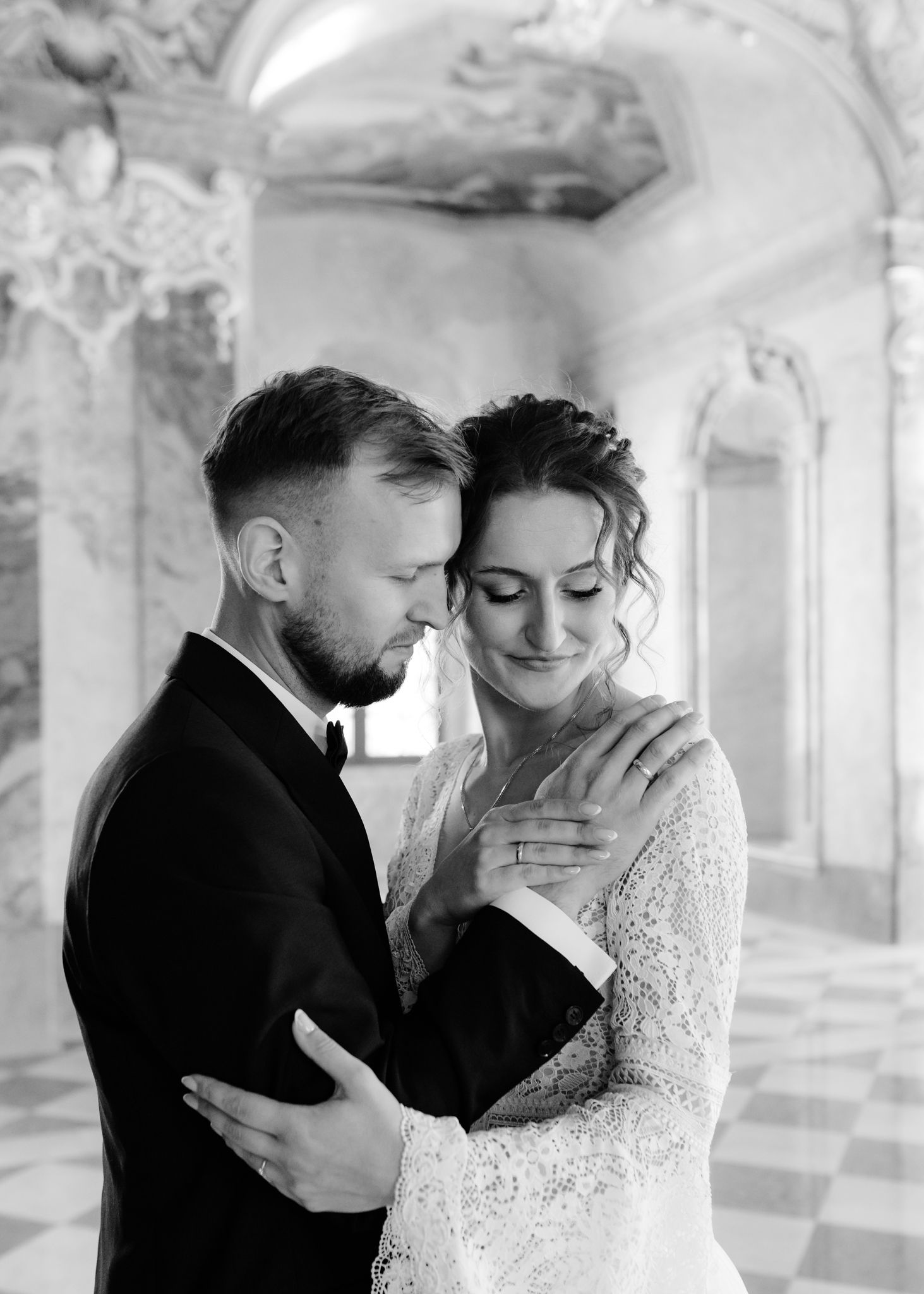 Black and white wedding portraits showing tender moments between newlyweds in an ornate interior.