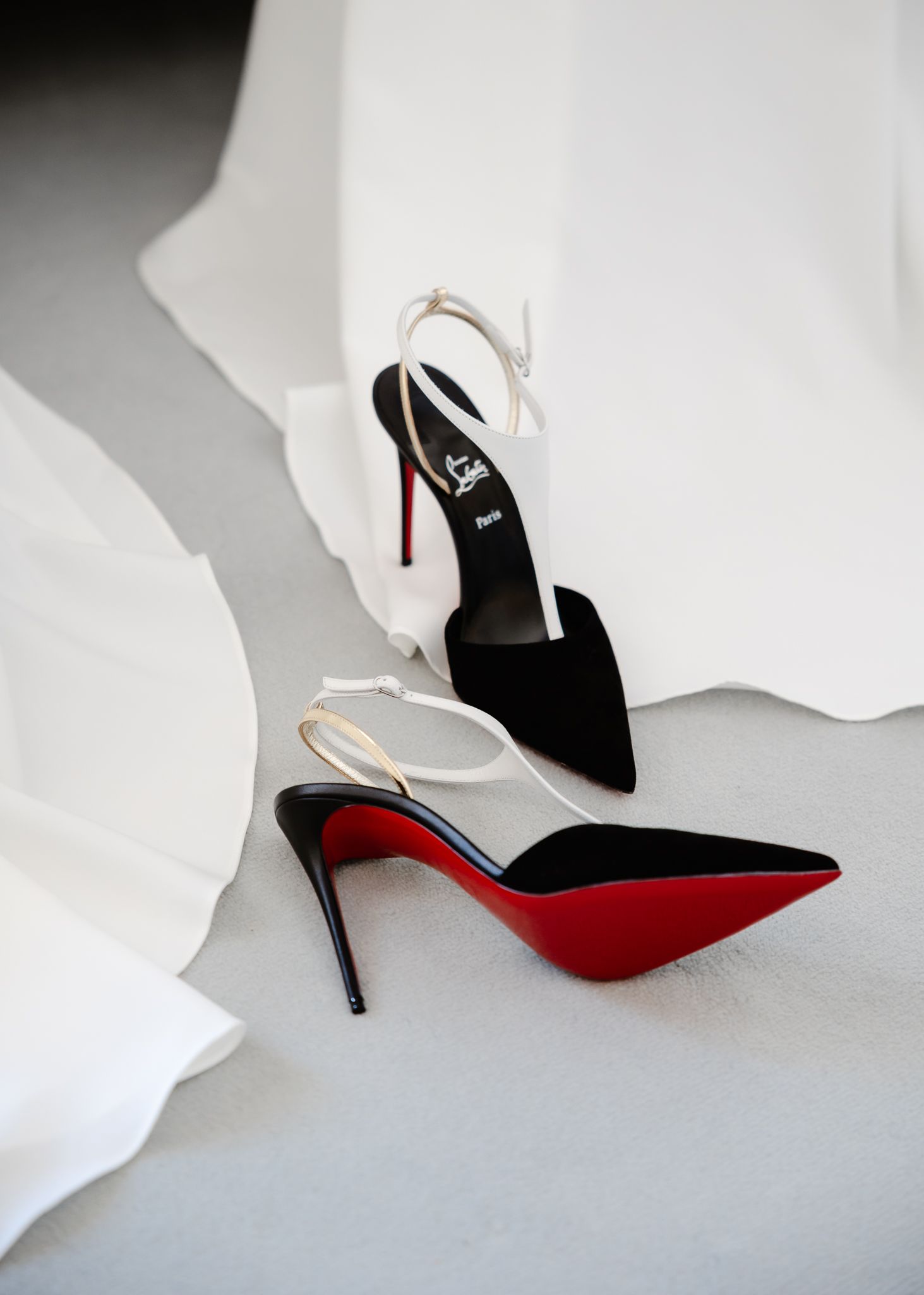 Elegant black slingback heels with red soles displayed against white fabric in multiple angles.