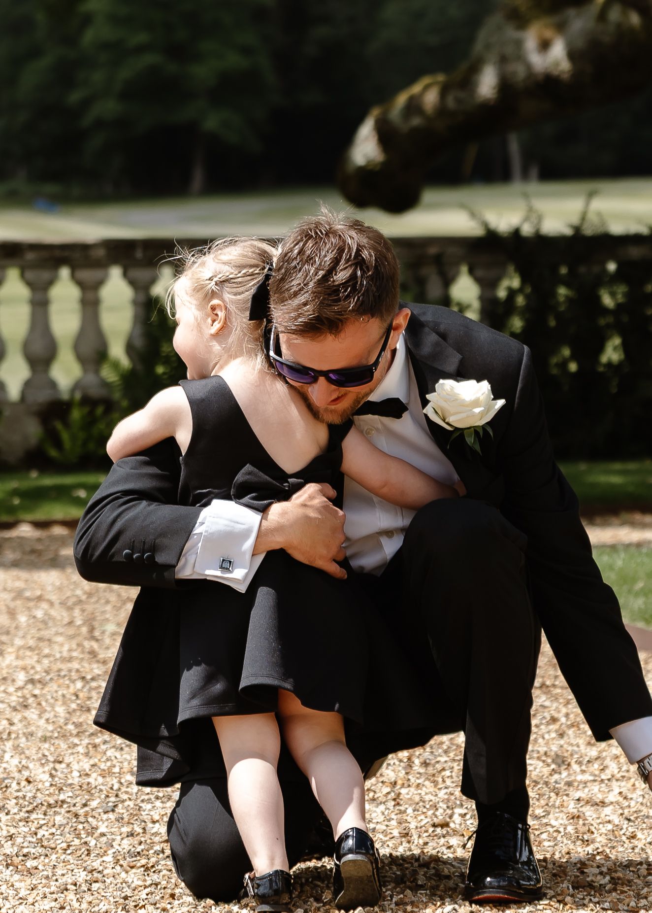 Playful wedding party poses on gravel path in formal attire for creative photo series.