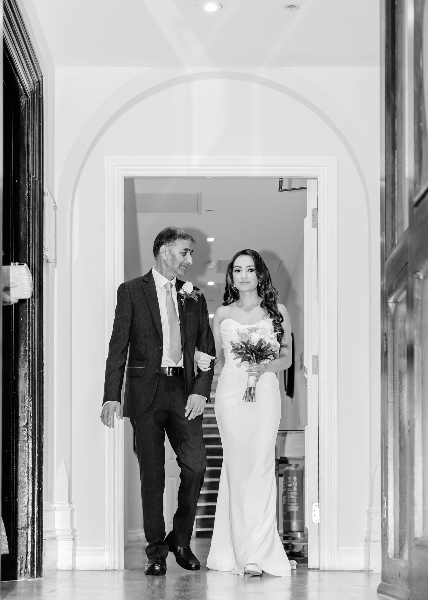 A series of black and white wedding photos showing a couple walking through an elegant hallway with arches.