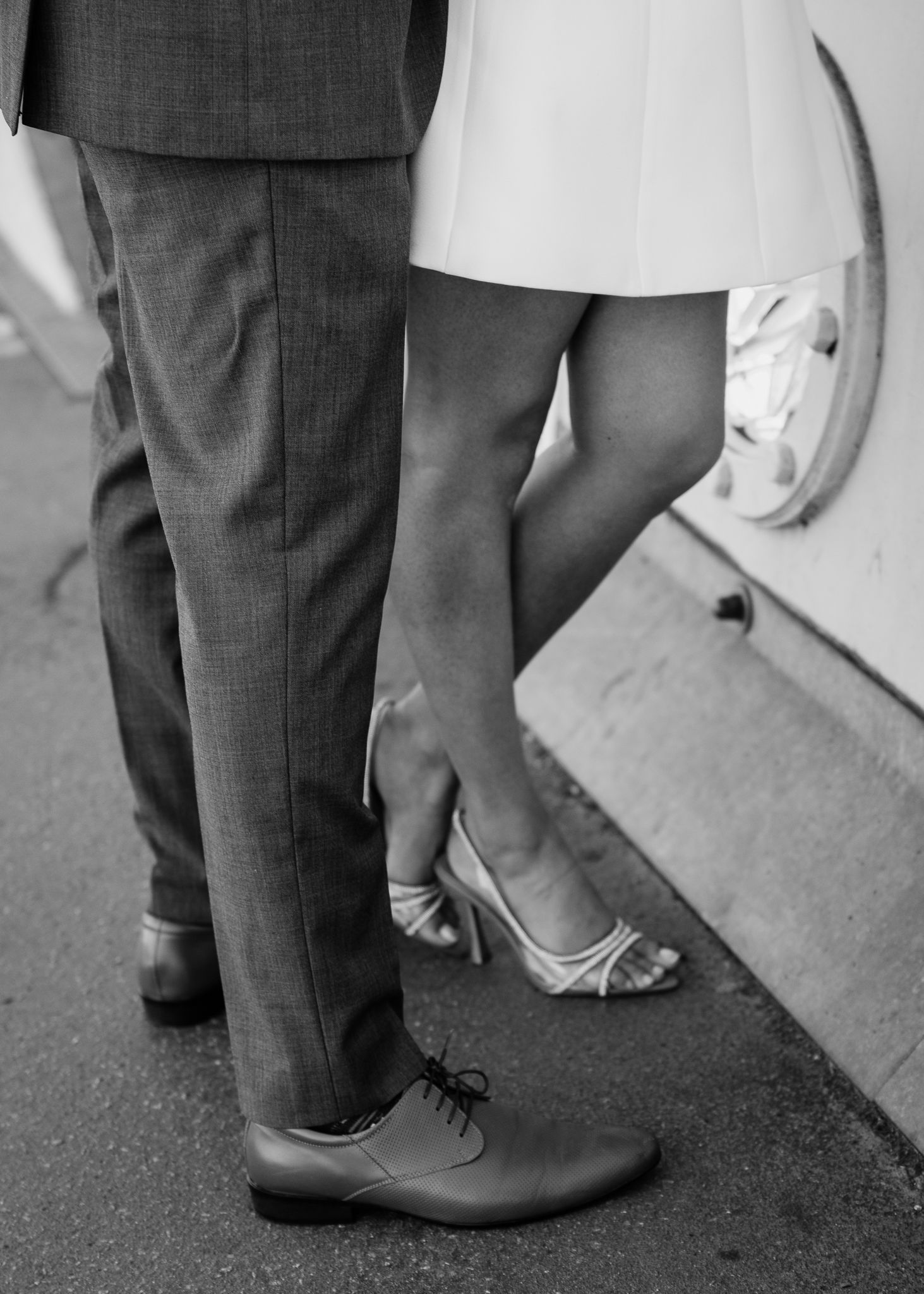 Black and white photo of couple's feet, man in dress shoes and woman in strappy heels.