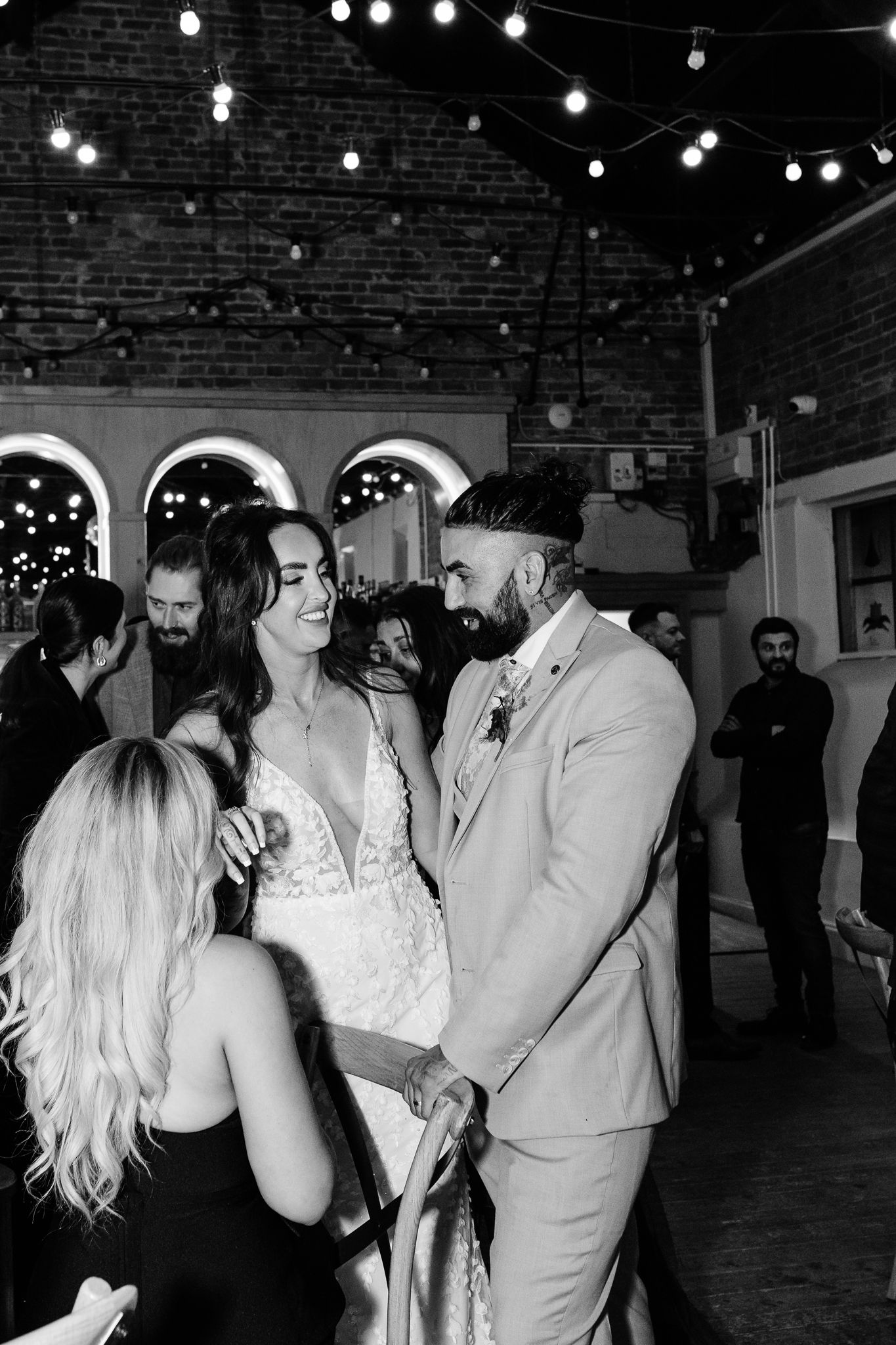 Wedding celebration in a rustic venue with string lights and exposed brick walls.