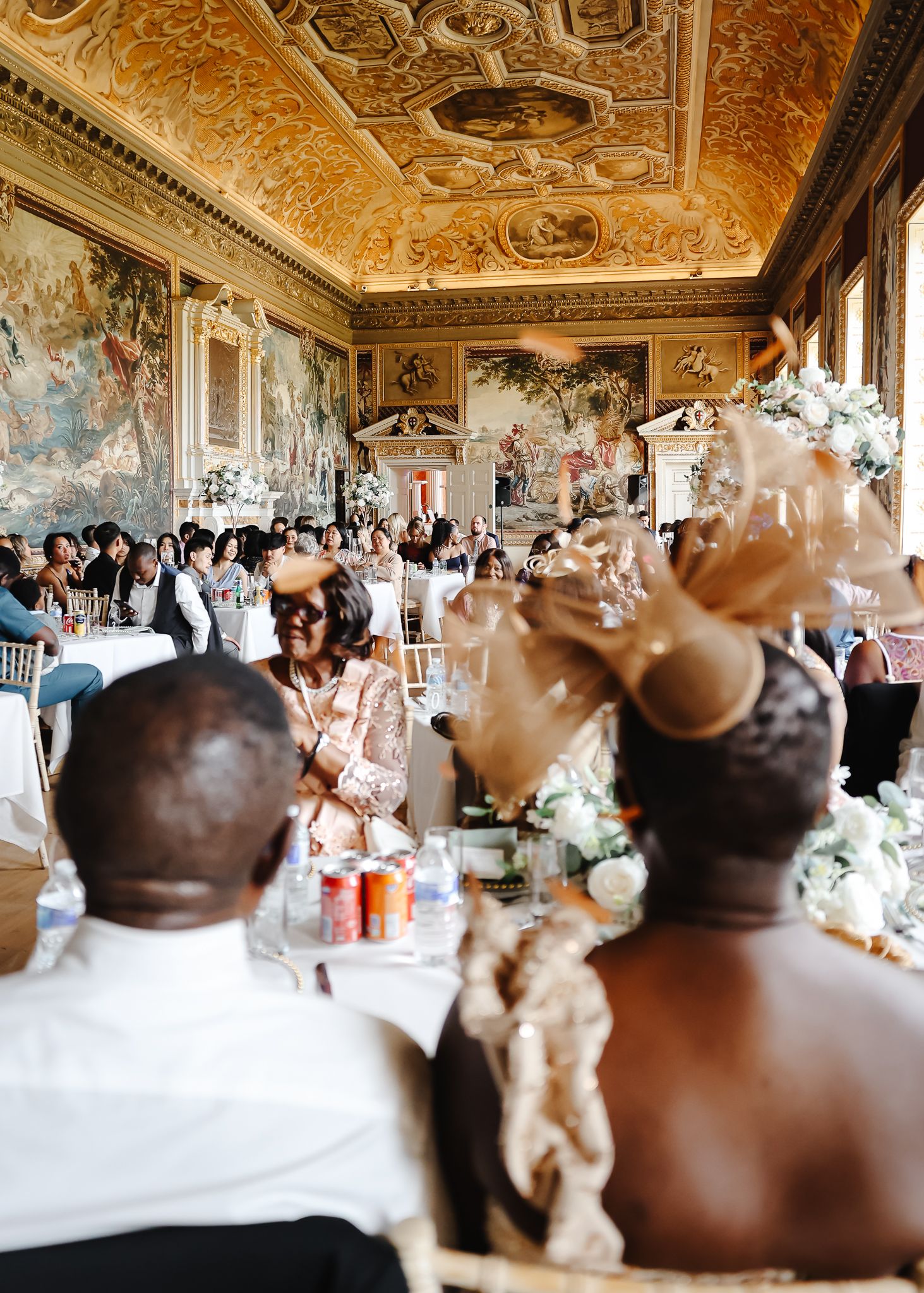 Ornate wedding reception in a grand baroque palace hall with elaborate ceiling frescoes and elegant table settings.