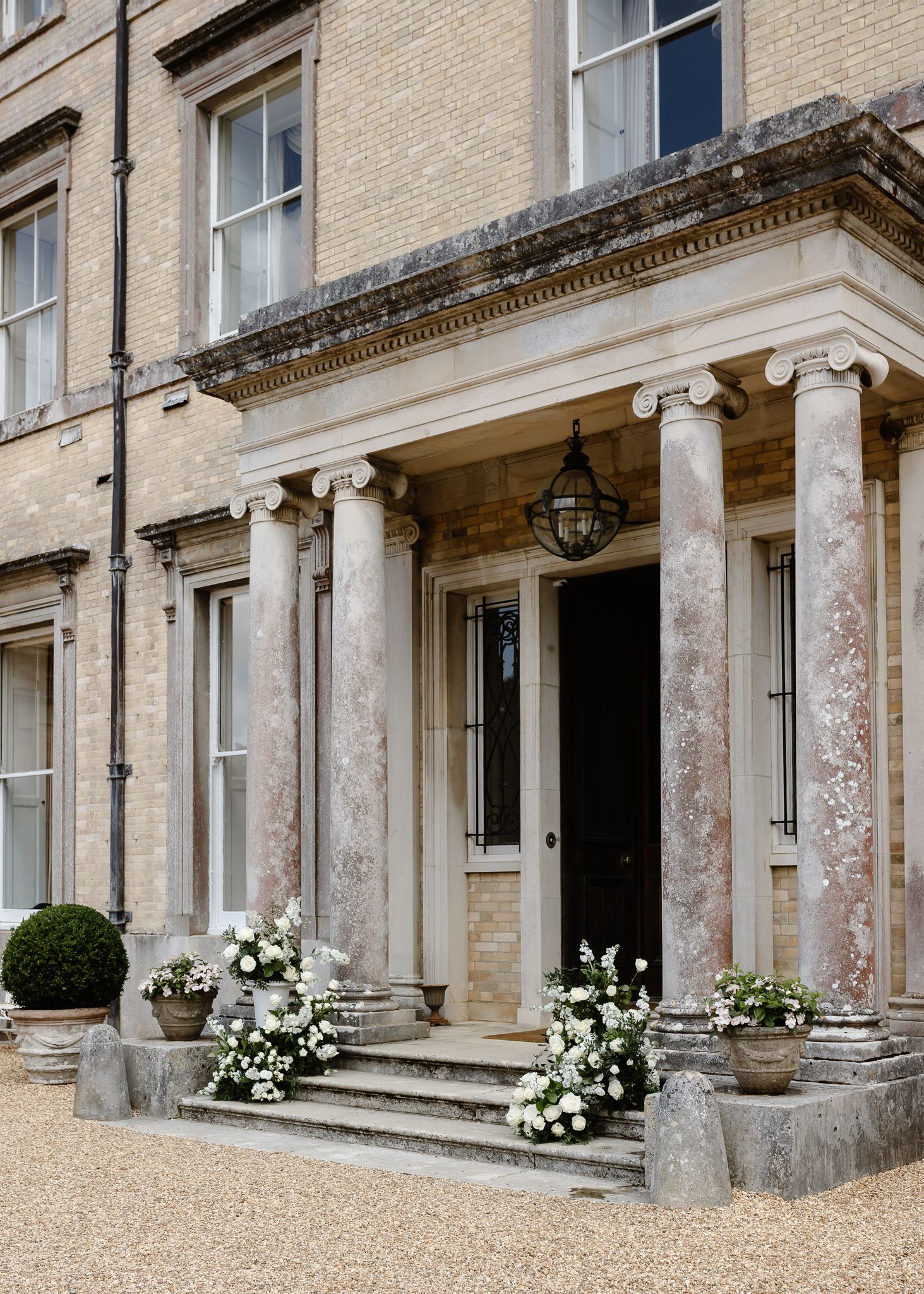 Elegant entrance with classical columns and white floral arrangements decorating the stone steps.