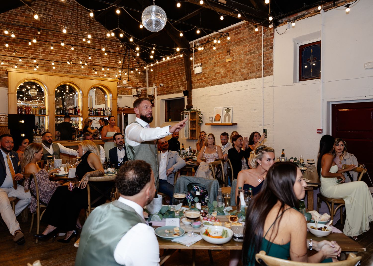 Wedding reception venue with exposed brick walls and twinkling string lights creating romantic ambiance.